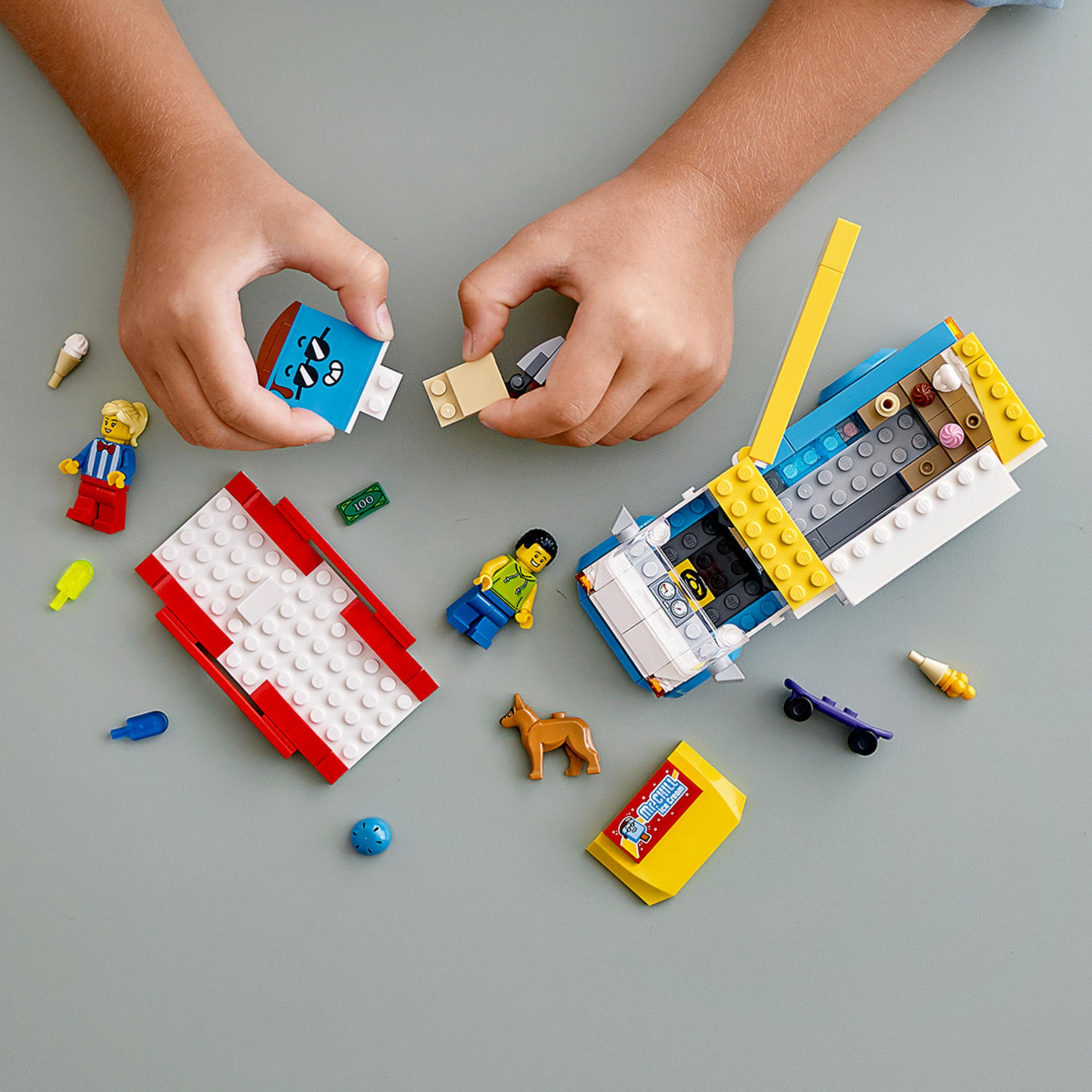 Ein Kind spielt mit LEGO-Steinen und Figuren. Die Szene beinhaltet ein Auto und Eis.