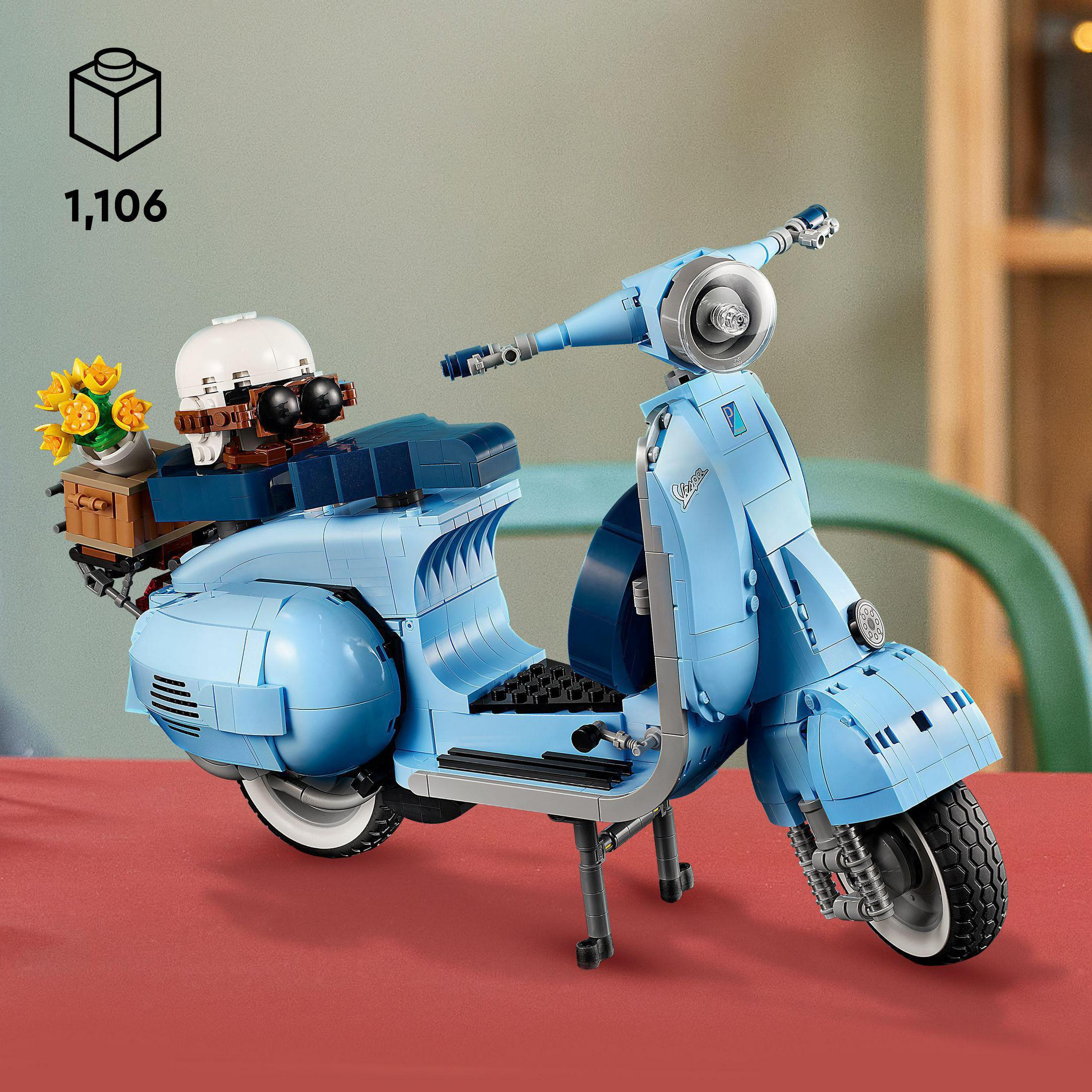 Jasnoniebieski model Lego Vespa z akcesoriami, na czerwonej powierzchni.