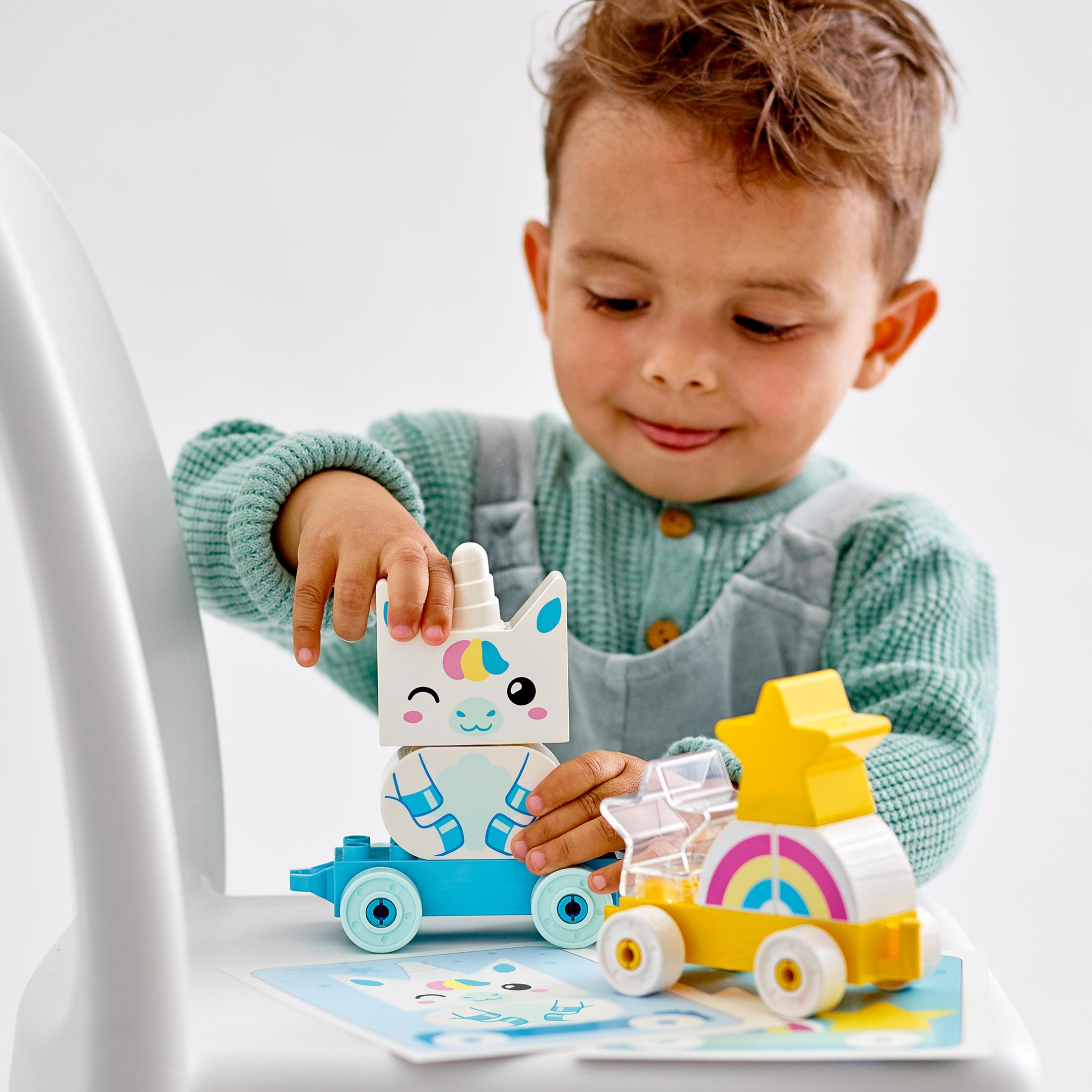 Ein Kind hält ein LEGO Einhorn und ein gelbes Auto mit einem Regenbogen.