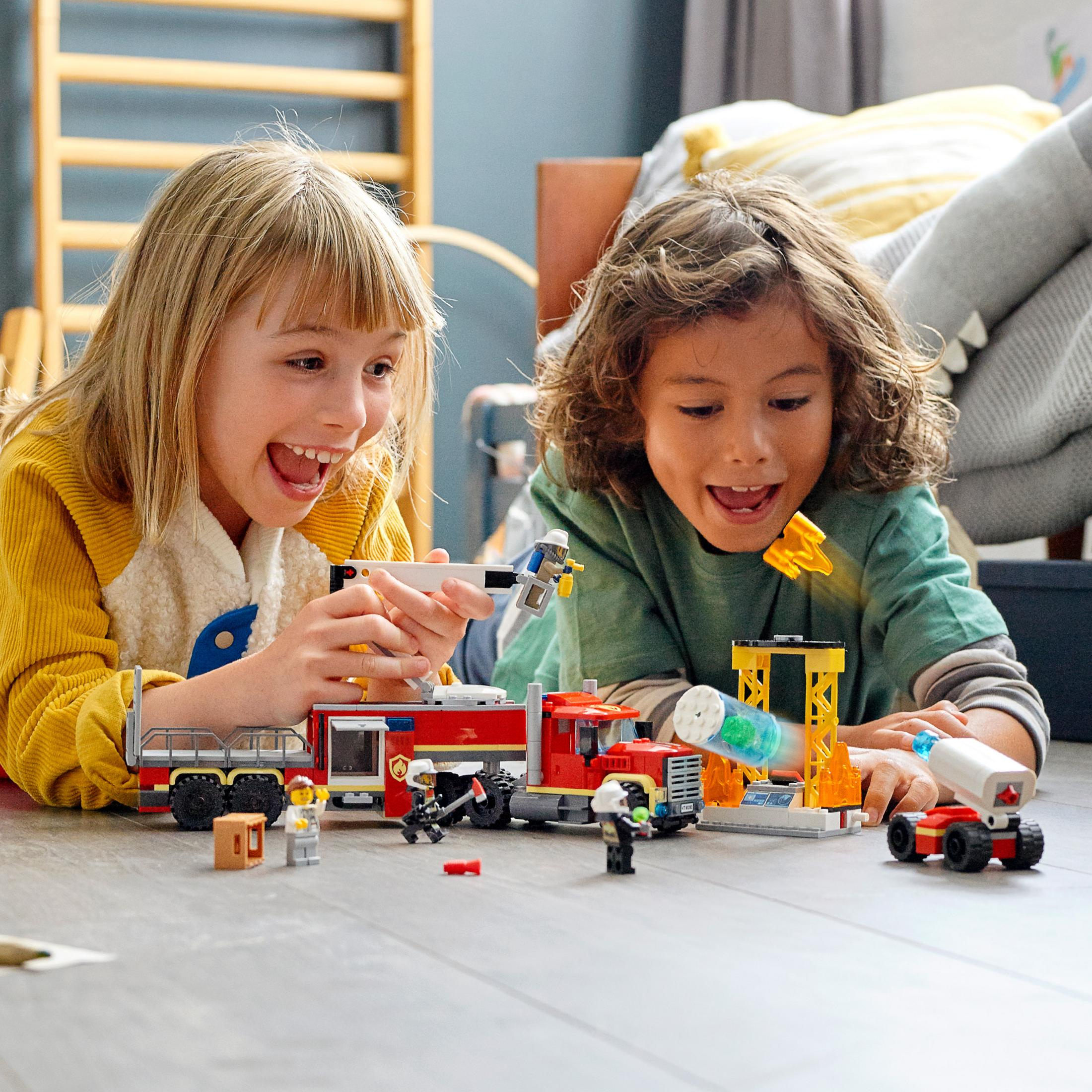 Due bambini giocano con un camion dei pompieri Lego e un set di costruzioni.
