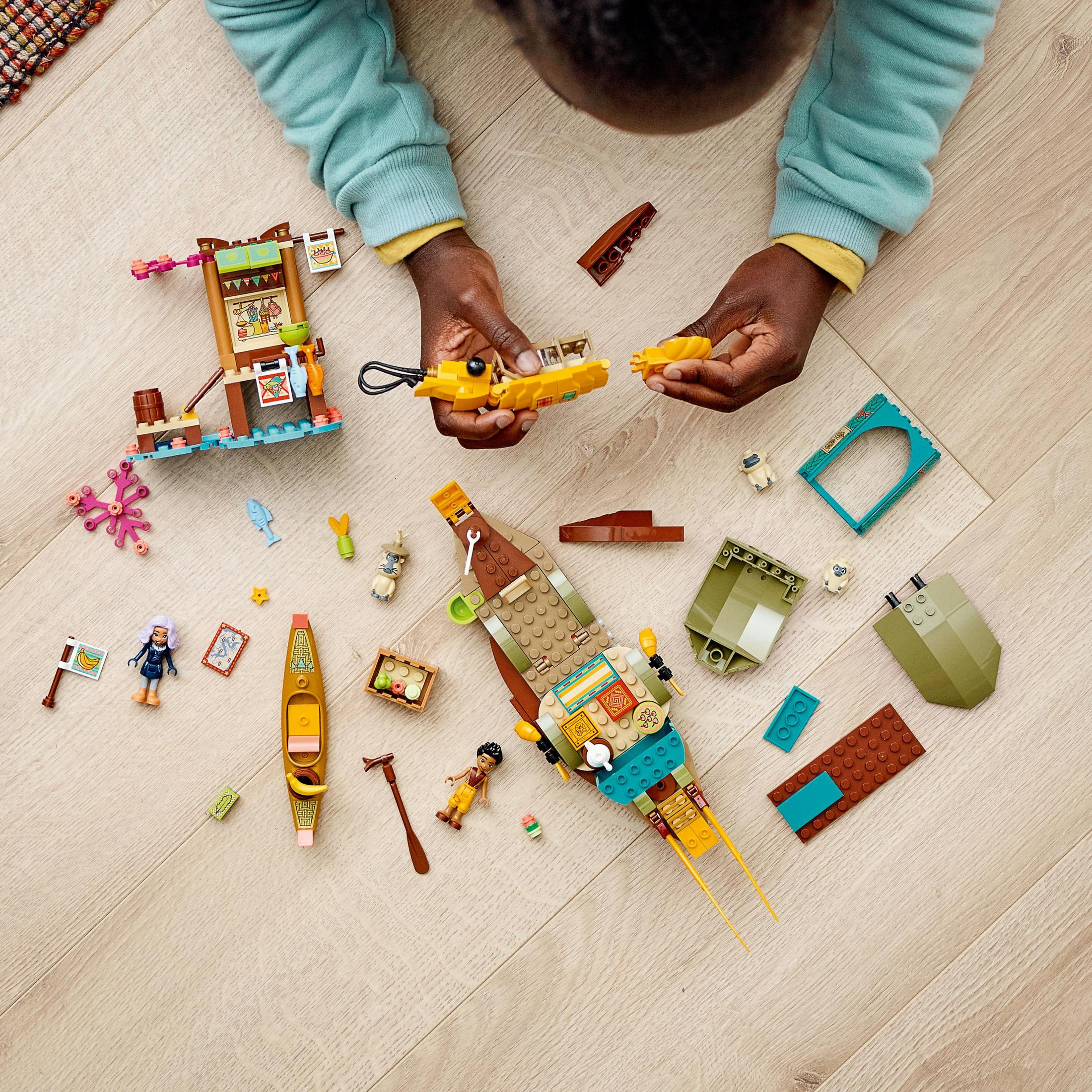 Dziecko bawiące się klockami LEGO, w tym łodzią i małymi figurkami.