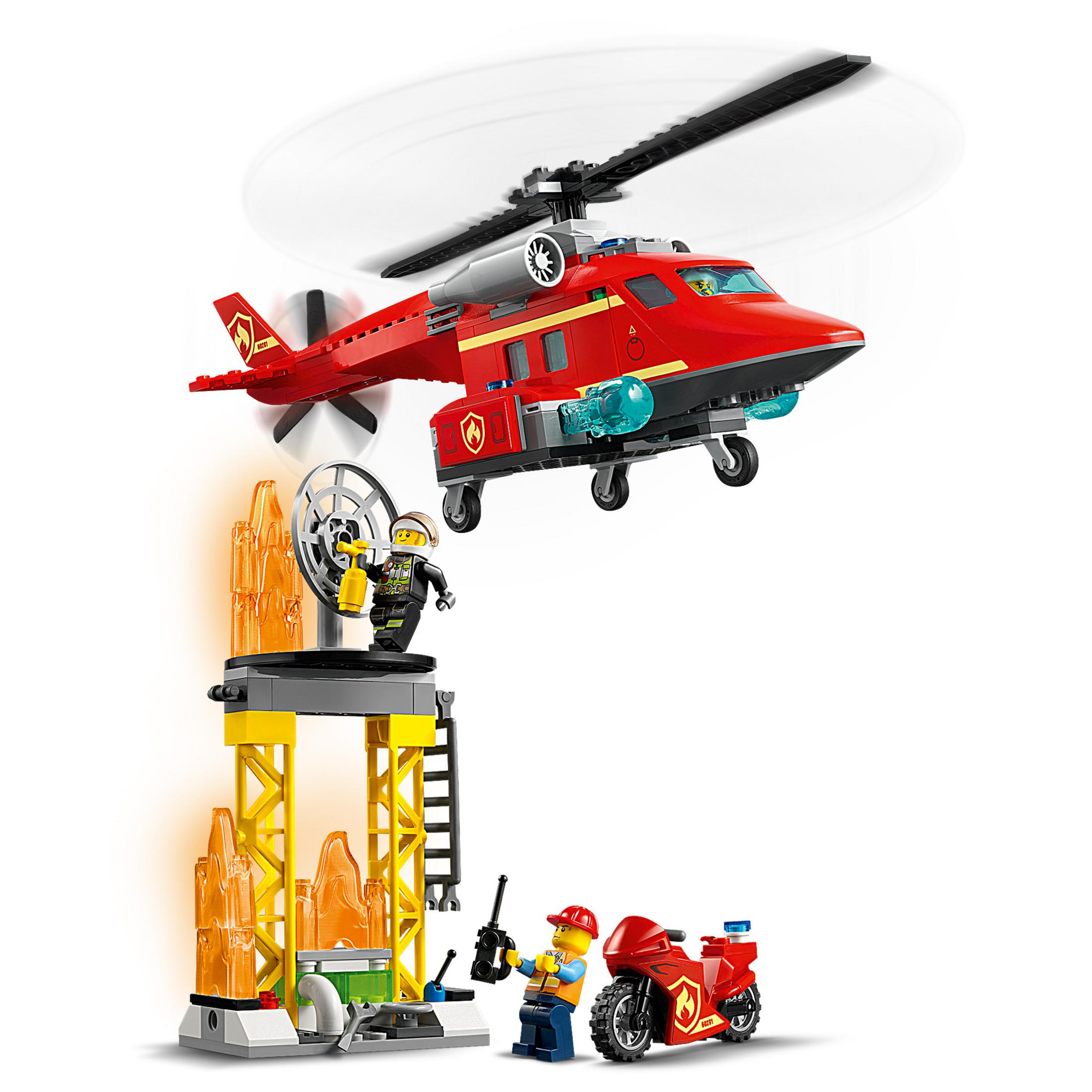 Ein roter Lego-Hubschrauber fliegt über einer Lego-Feuerwehrszene mit Figuren.