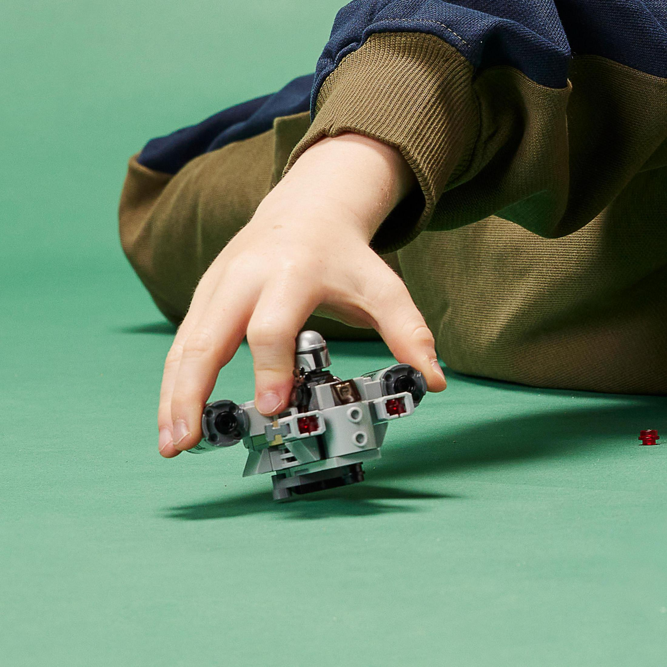 Die Hand eines Kindes hält ein Lego-Raumschiff-Spielzeug. Das Spielzeug ist grau, mit roten und schwarzen Akzenten.