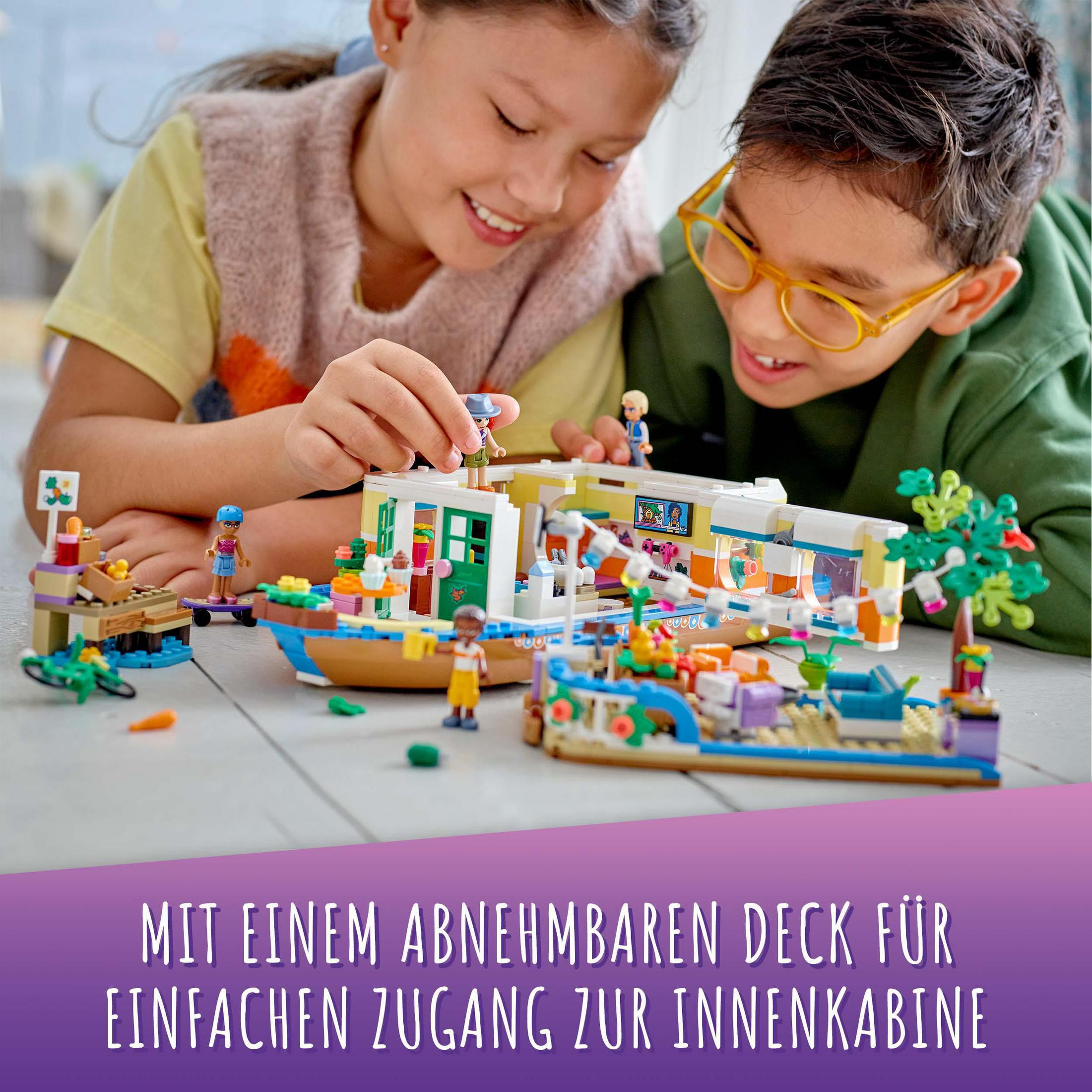 Kinder spielen mit einem Lego-Set. Text lautet: „MIT EINEM ABNEHMBAREN DECK FÜR EINFACHEN ZUGANG ZUR INNENKABINE“.