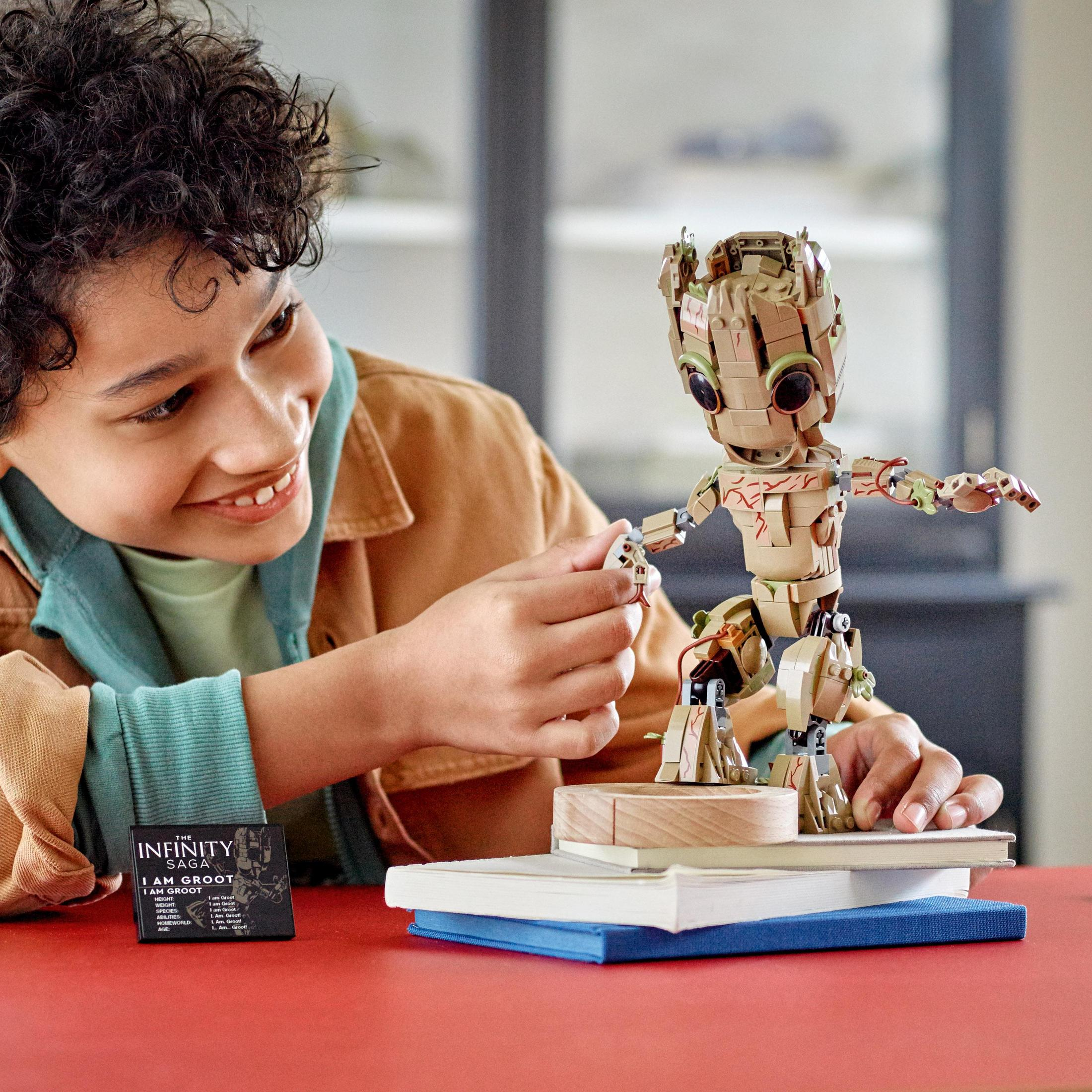 Ein Junge spielt mit einer Lego Groot Figur. Die Figur ist braun und beige.
