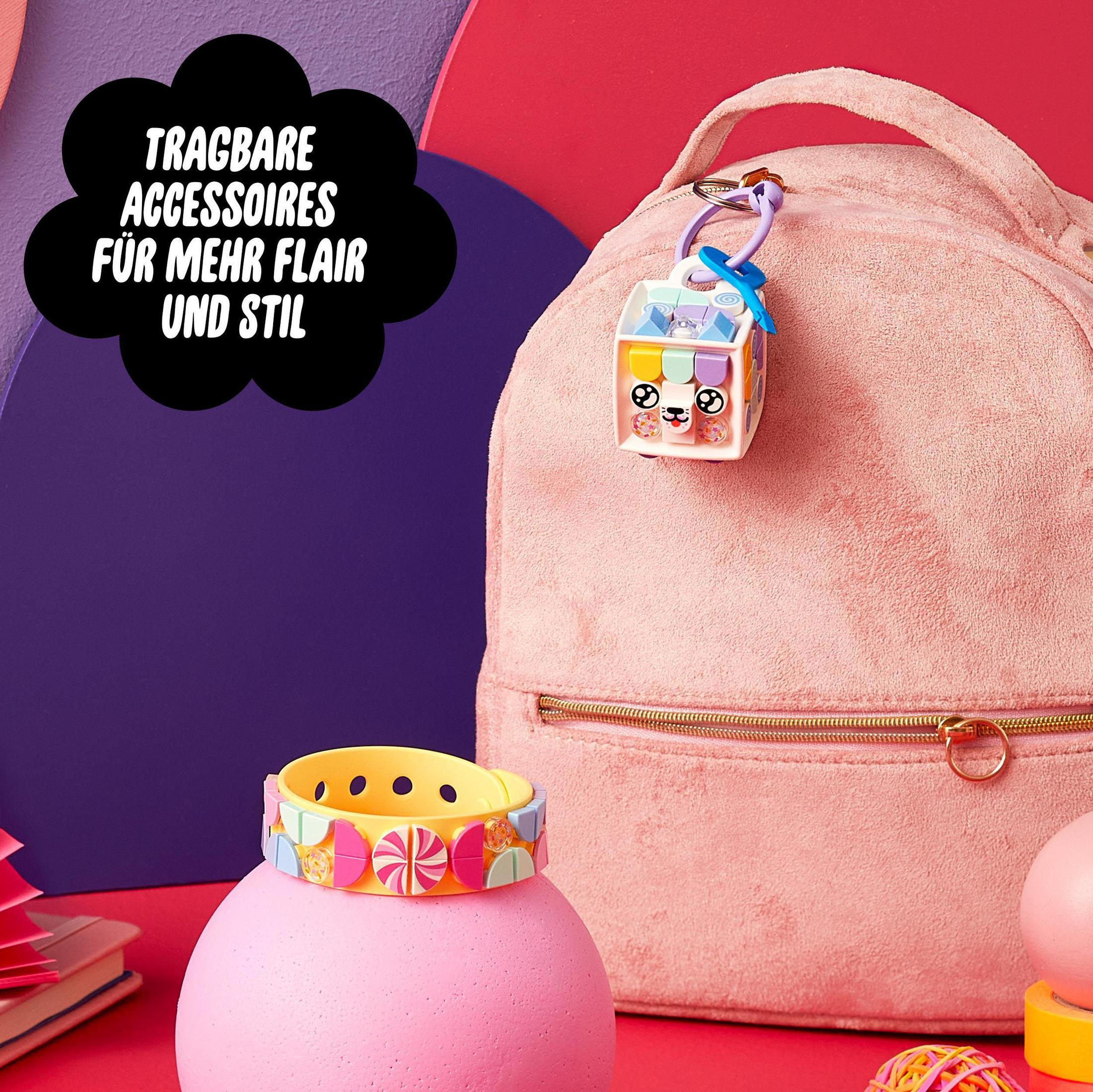 Ein pinkfarbener Rucksack, ein kleiner Würfel mit Schlüsselring und ein buntes Armband werden gezeigt.