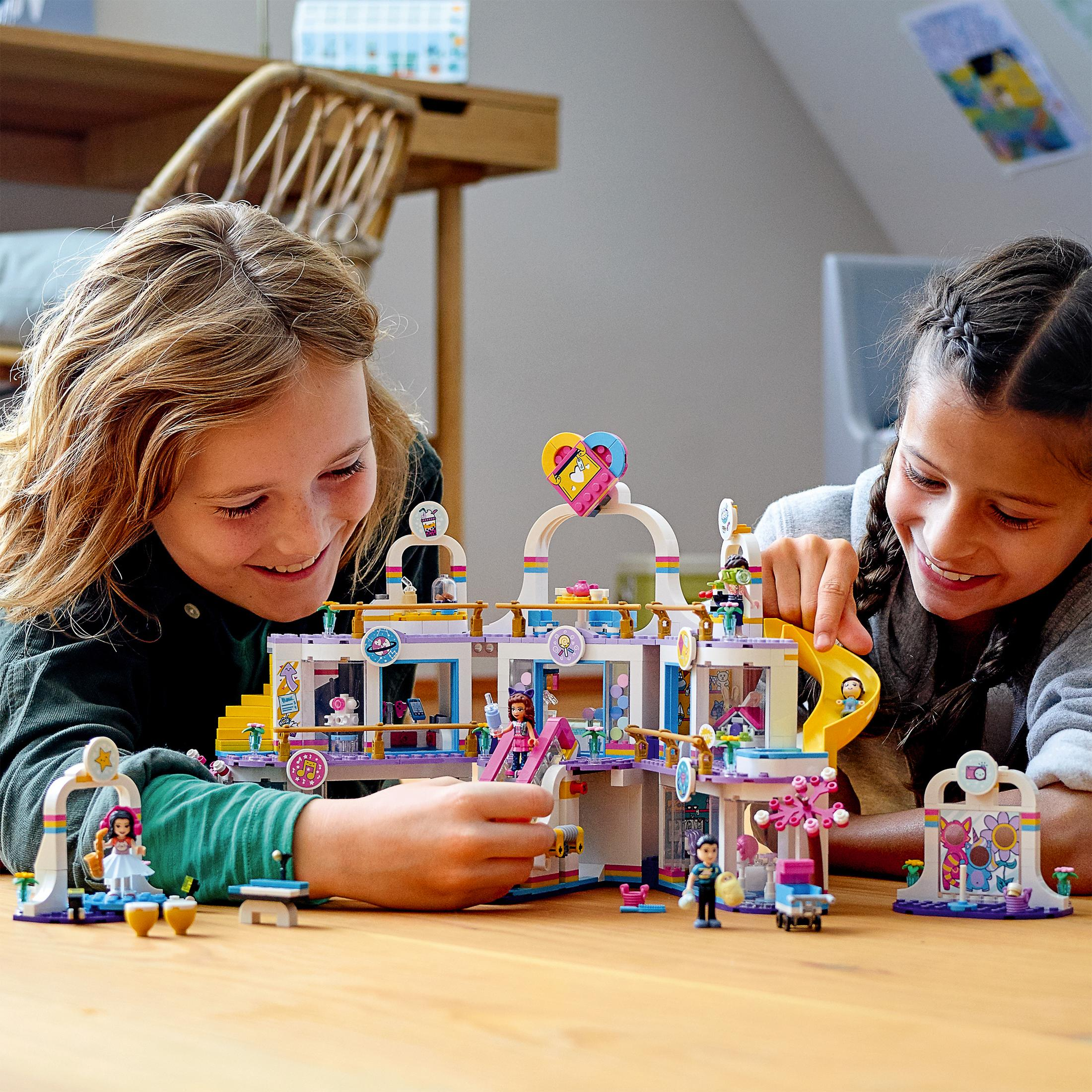 Zwei Mädchen spielen mit einem Lego-Set. Das Set ist ein farbenfrohes Gebäude mit Menschen und Blumen.