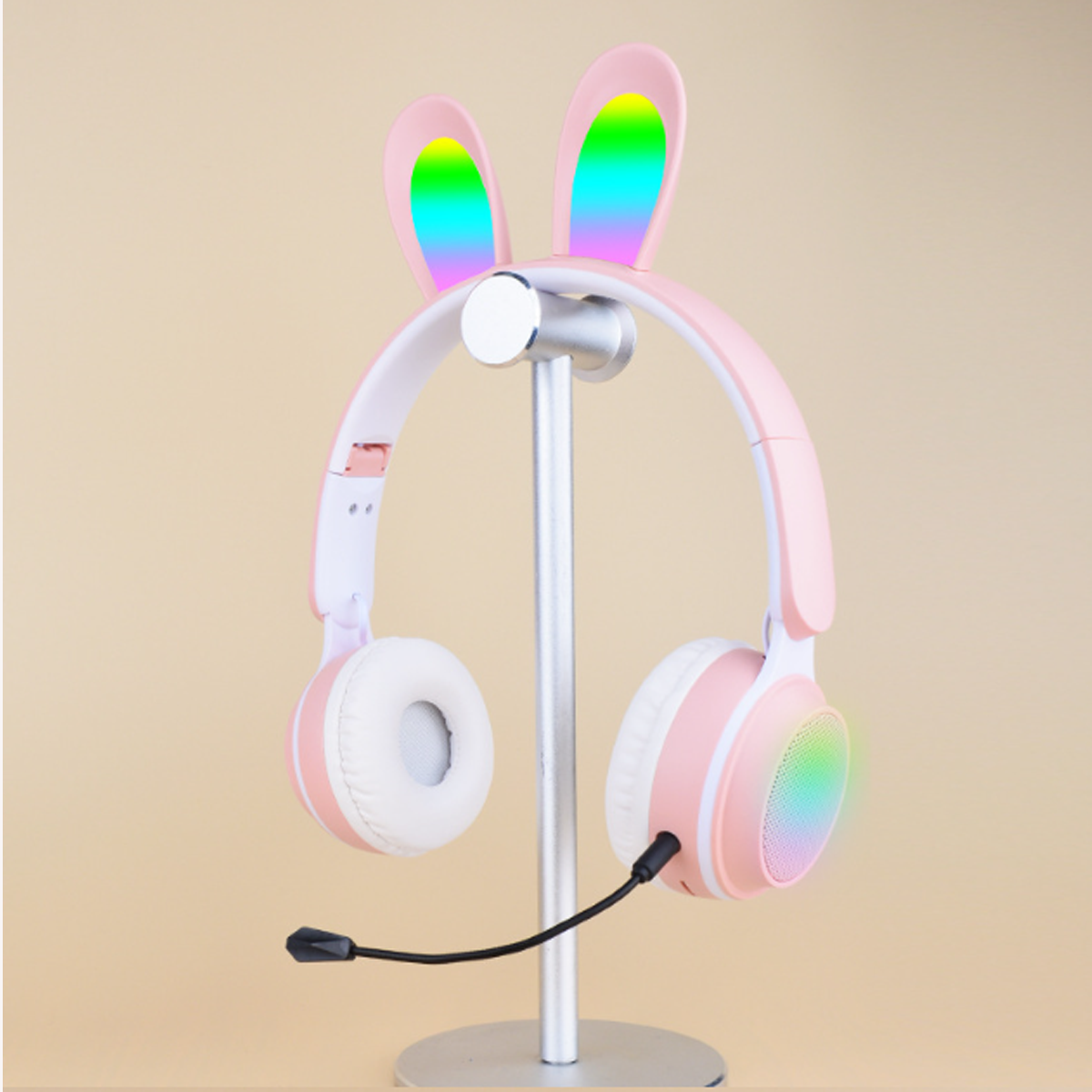 Rosa Hasenohrkopfhörer auf einem Ständer. Die Ohren zeigen ein Regenbogenmuster.