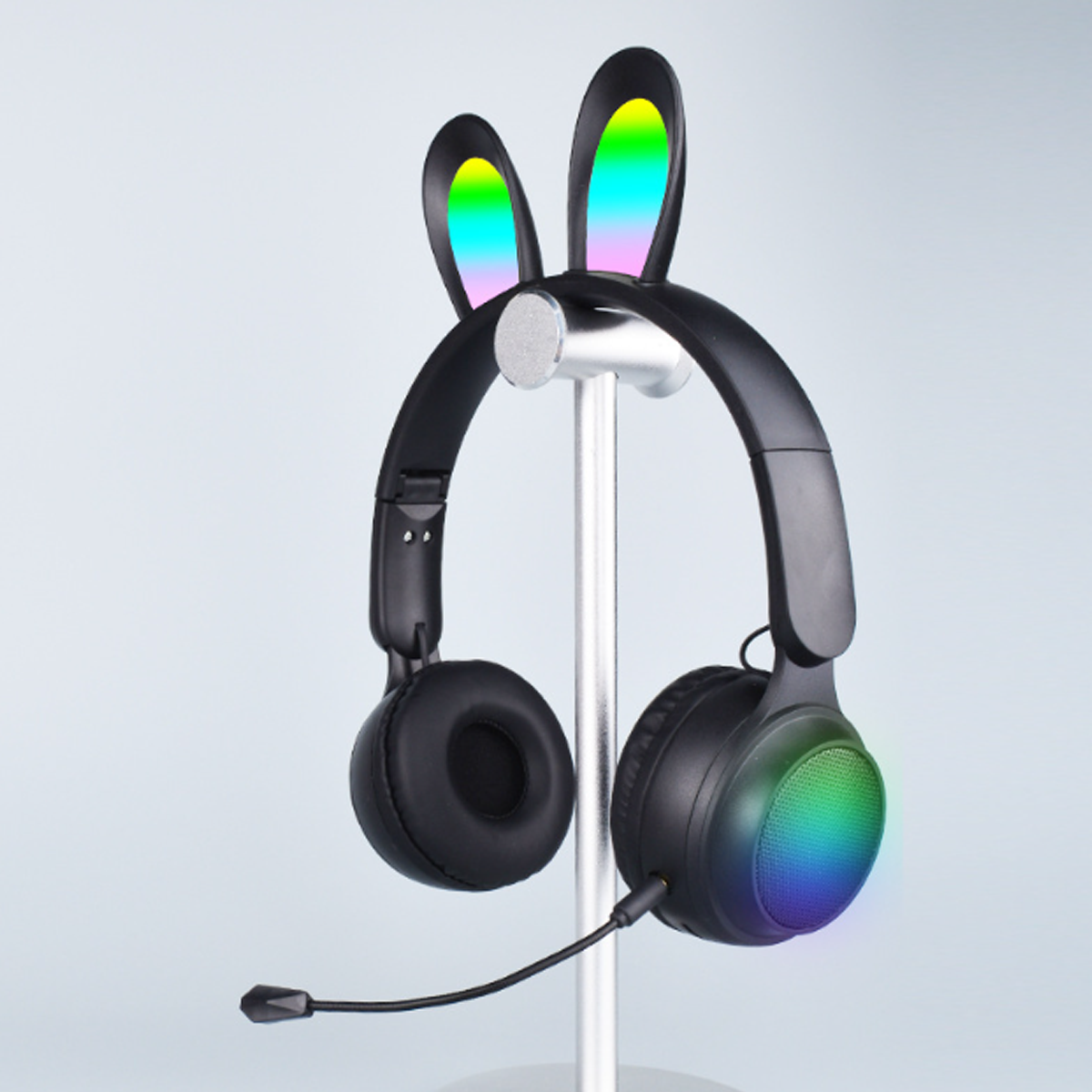 Schwarze Kopfhörer mit Hasenohren. Die Ohren und Ohrmuscheln haben Regenbogenfarben. Auf einem Ständer.
