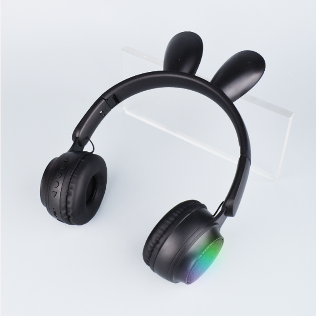 Schwarze Kopfhörer mit Hasenohren-Design auf weißer Oberfläche. Die Ohrmuscheln haben farbige Lichter.