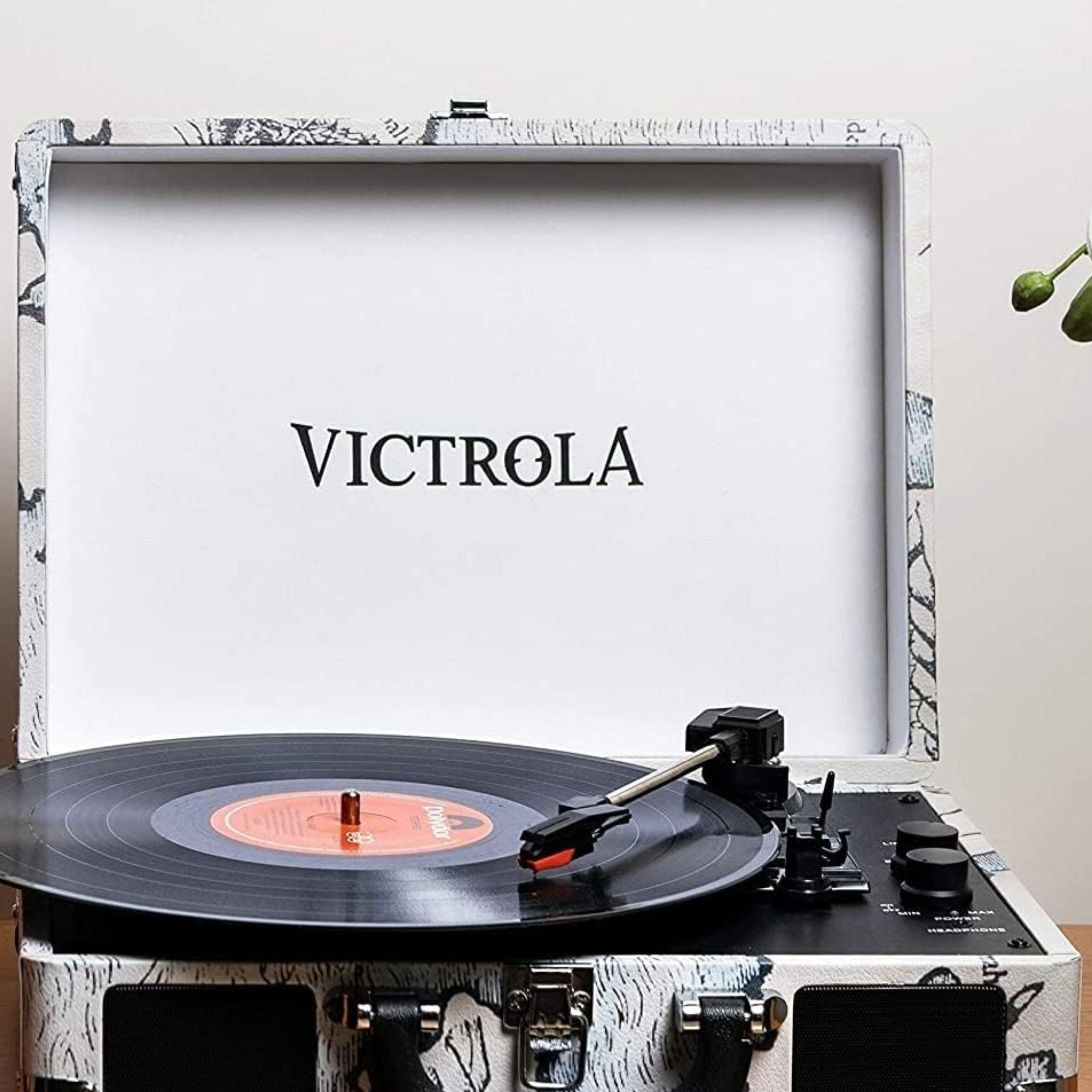 Un tocadiscos Victrola con un disco de vinilo negro reproduciéndose. El logotipo de Victrola es visible.