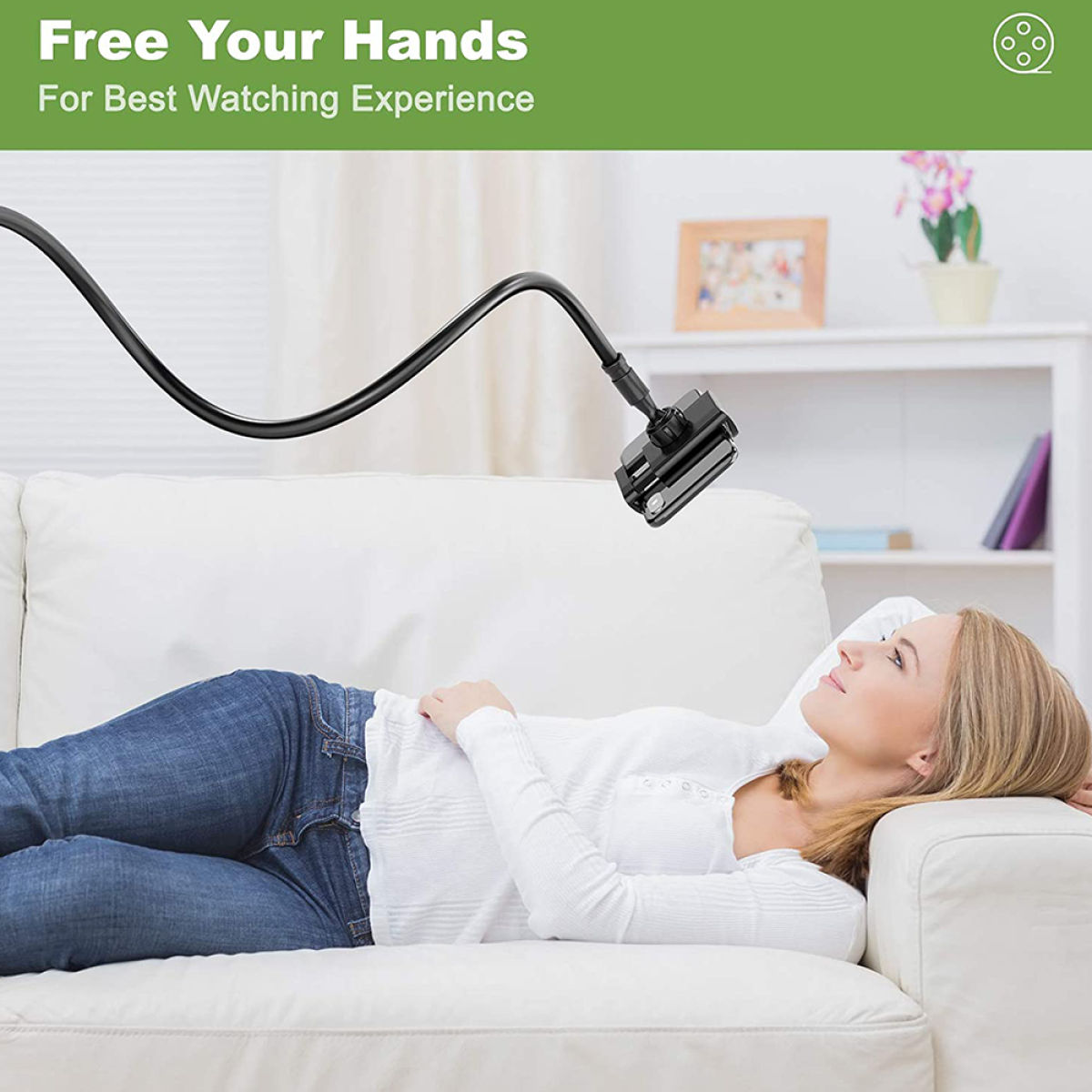 Frau liegt auf einem Sofa mit einem Telefon an einem flexiblen Arm. Gemälde und Pflanzen sichtbar.