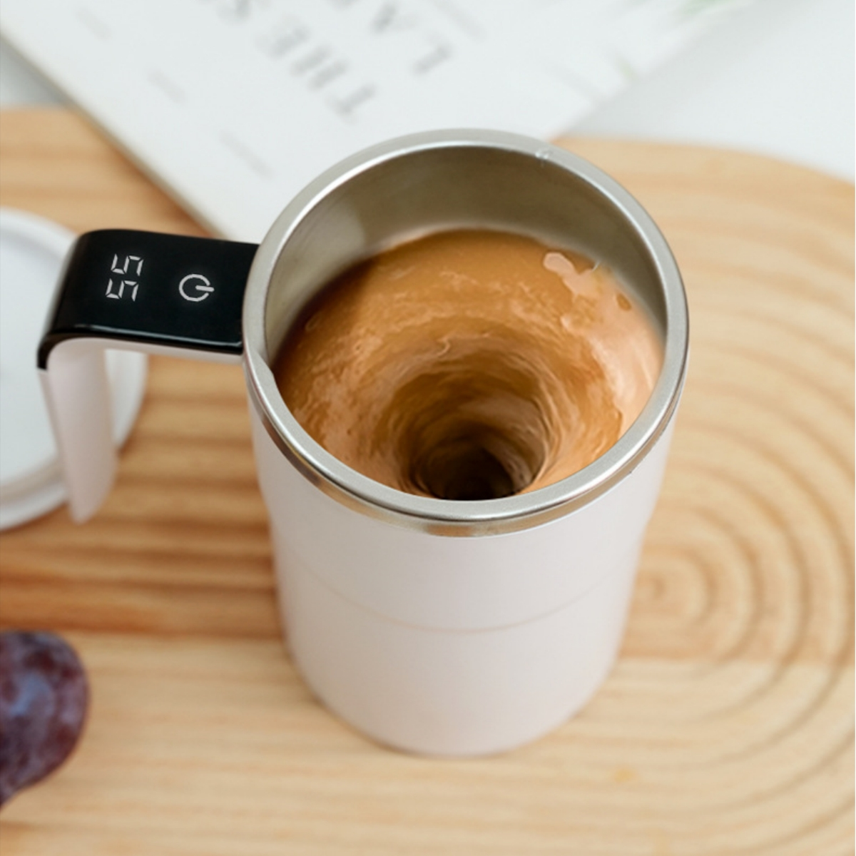 Ein weißer Becher mit silbernem Rand, der eine braune Flüssigkeit enthält, die gewirbelt wird, auf einer Holzoberfläche.