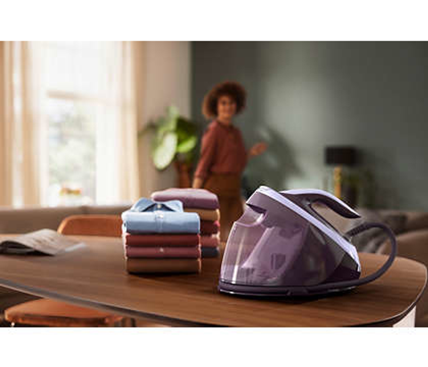 Configuración de planchado: plancha, pila de ropa y mujer. La plancha es morada.