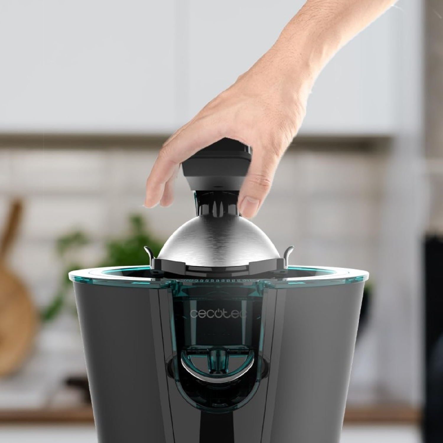 Una mano coloca la parte superior de un exprimidor de cítricos negro y plateado sobre la base.