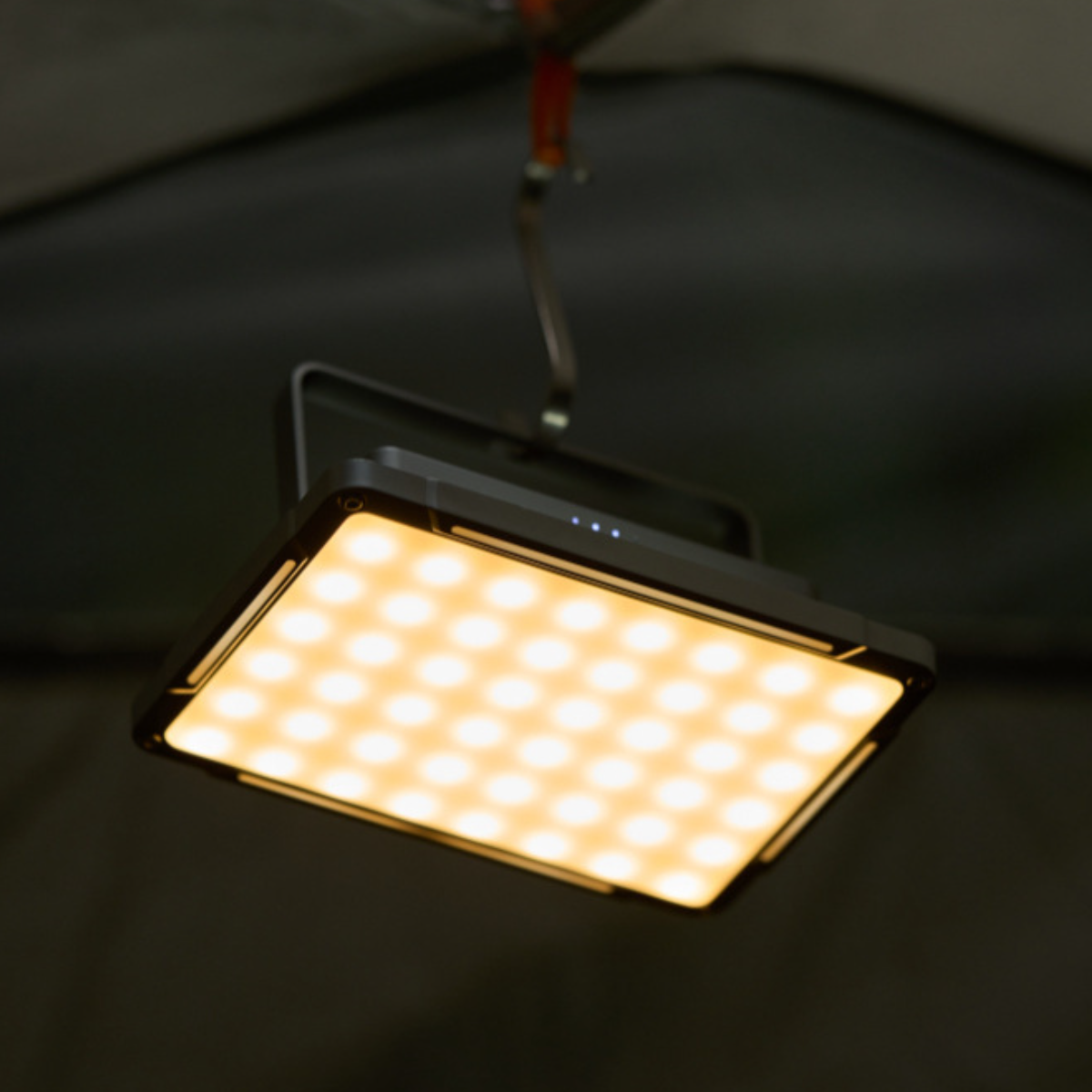 Eine quadratische LED-Leuchte, die von oben hängt, mit grauem Rahmen und schwarzem Hintergrund.