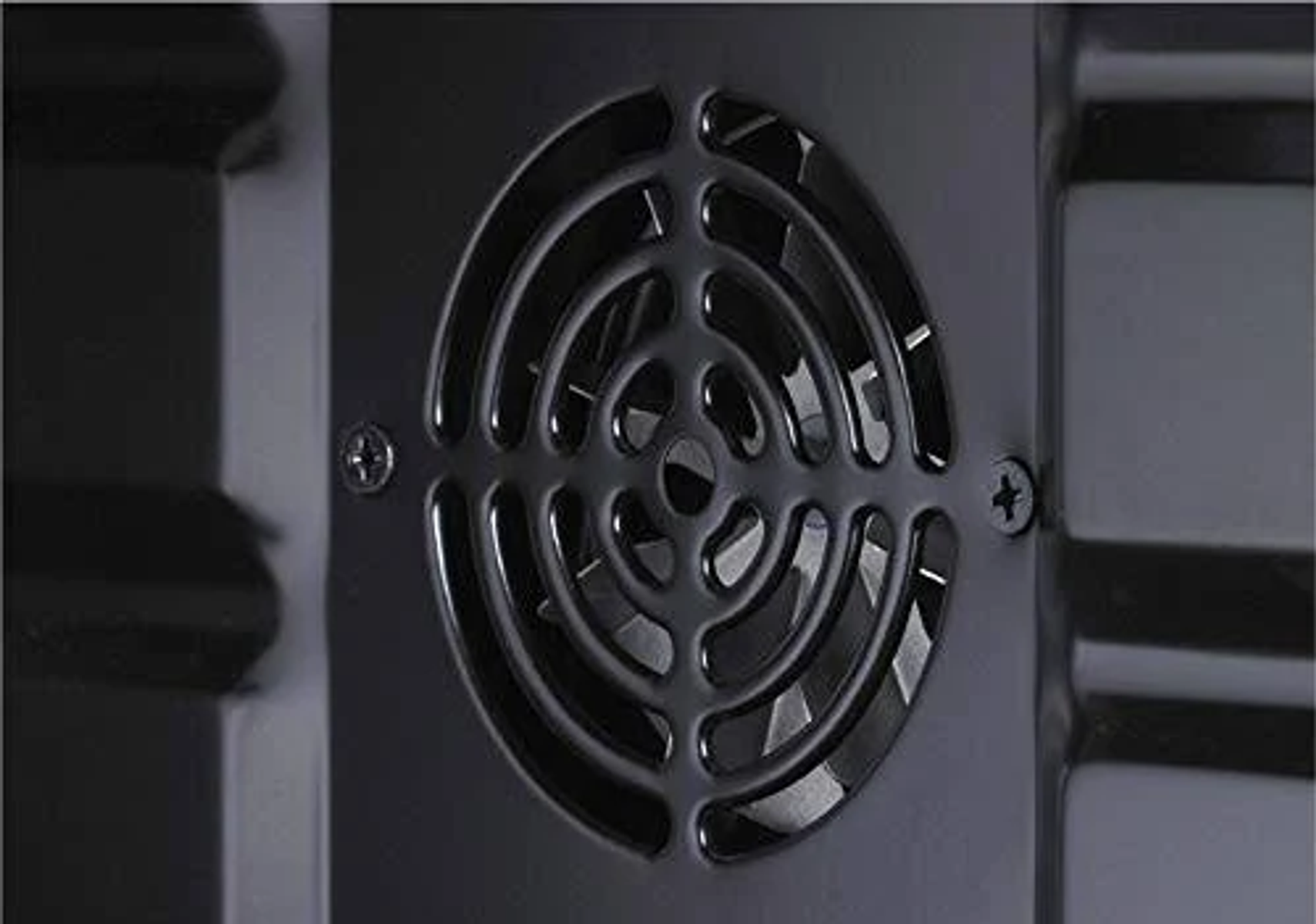 Zbliżenie okrągłego wentylatora wewnątrz ciemnego, metalicznego urządzenia.