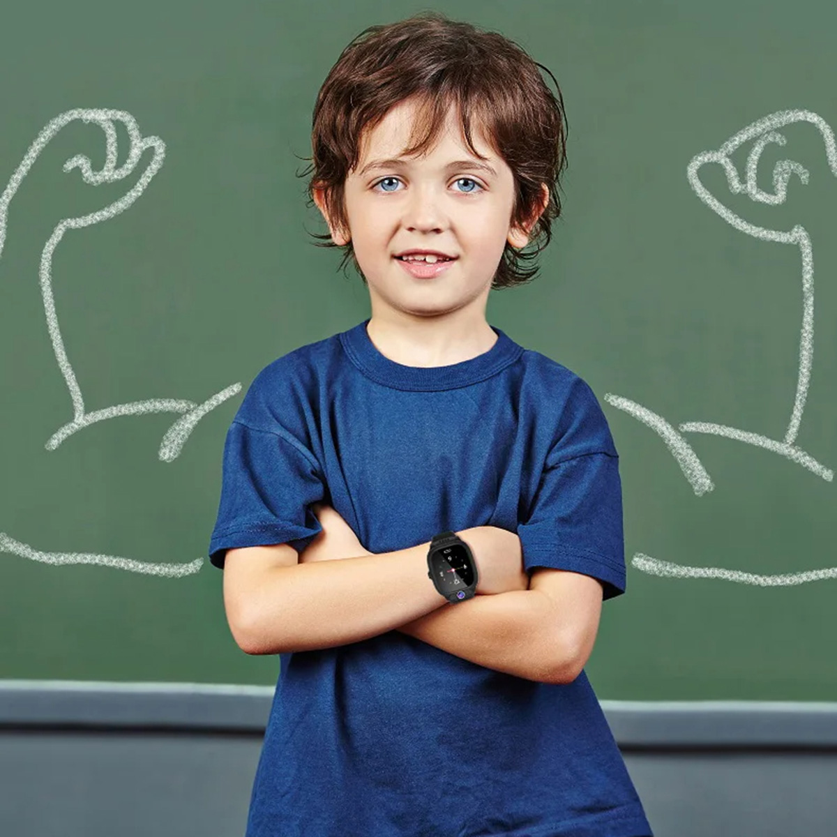 Un niño sonríe, camisa azul y smartwatch, brazos cruzados, con pizarra detrás.
