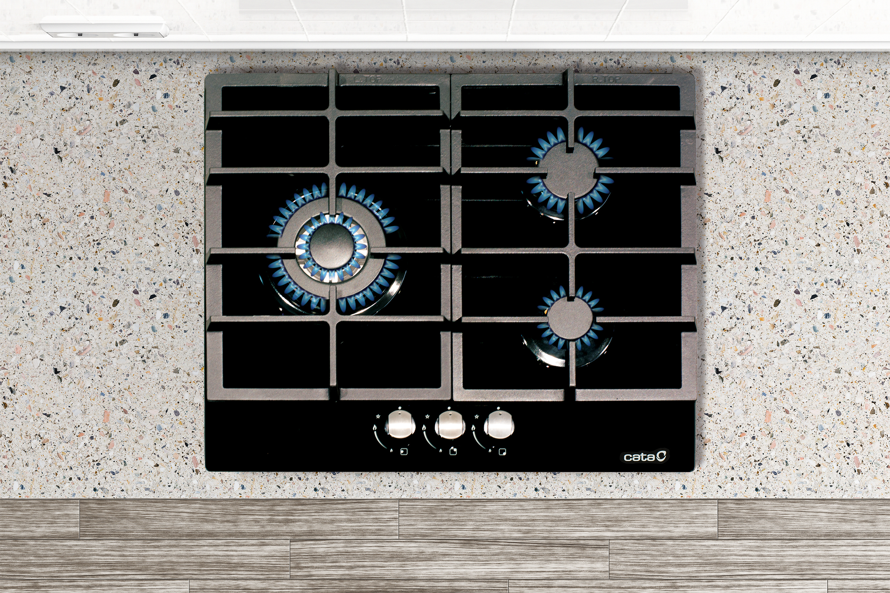 Czarna płyta gazowa na nakrapianym blacie. Trzy palniki są zapalone niebieskimi płomieniami.