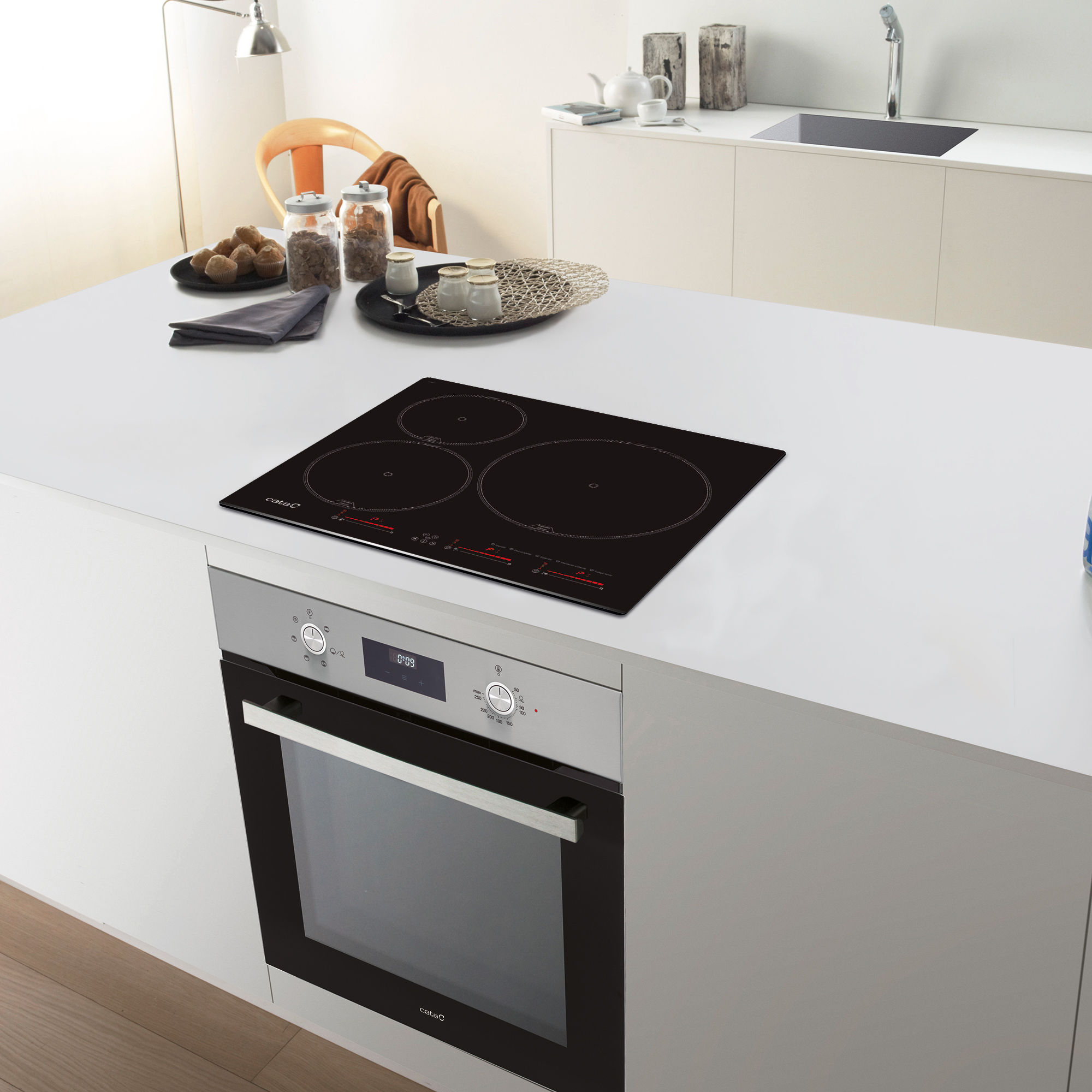 Una isla de cocina moderna con una placa de cocina negra y horno, y algunos objetos.