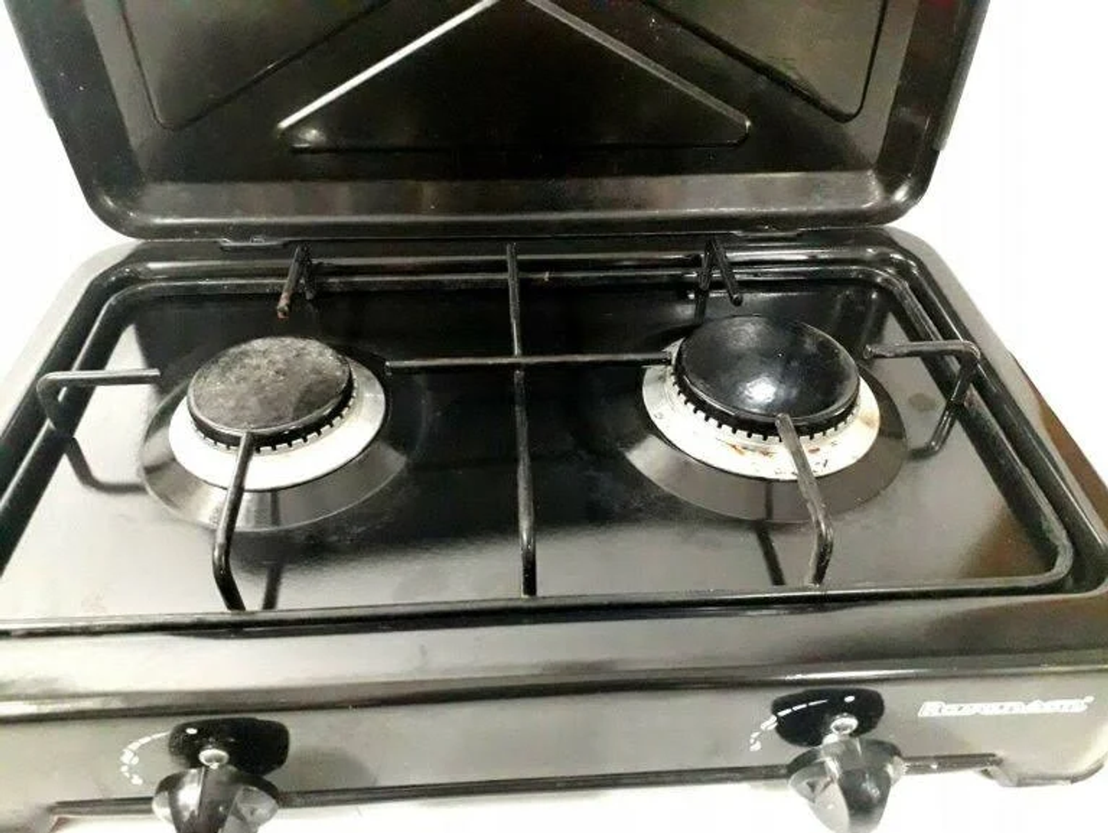 Czarna kuchenka gazowa z dwoma palnikami i otwartymi pokrywami. Widoczne pokrętła.