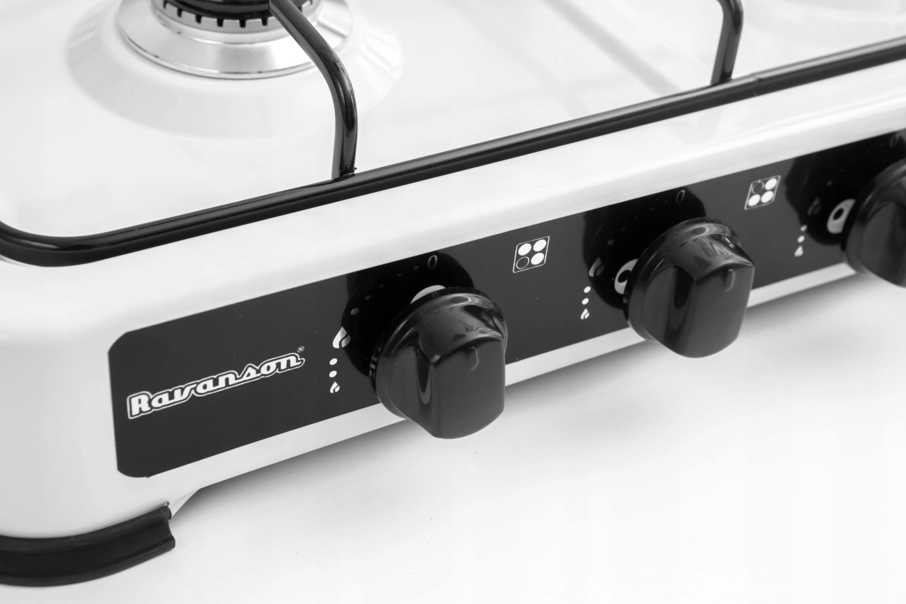 Zbliżenie białej i czarnej kuchenki gazowej, pokazujące pokrętła i palniki.