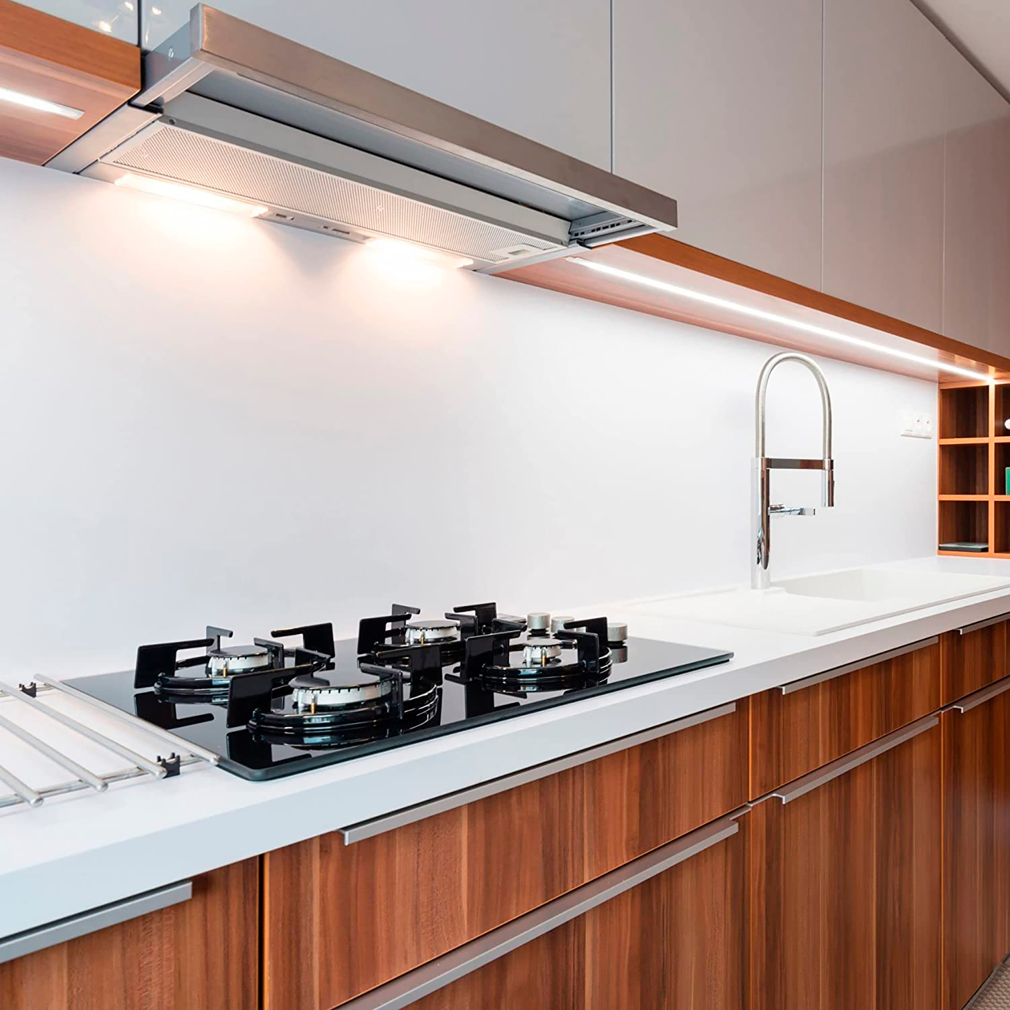 Cocina con gabinetes de madera, encimera blanca y cocina a gas.
