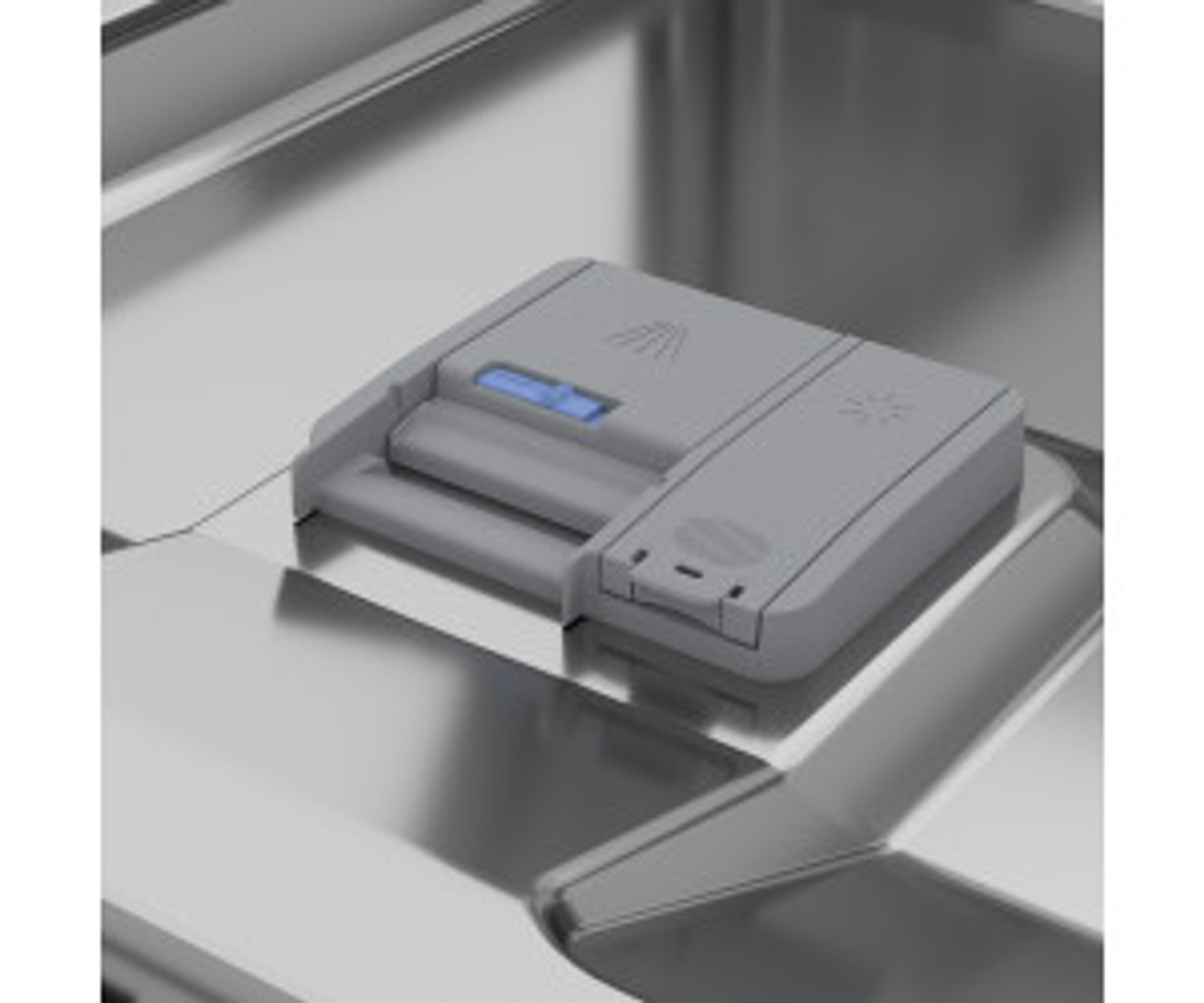 Dispensador de detergente para lavavajillas, dentro de un lavavajillas de acero inoxidable. El dispensador es de plástico gris.