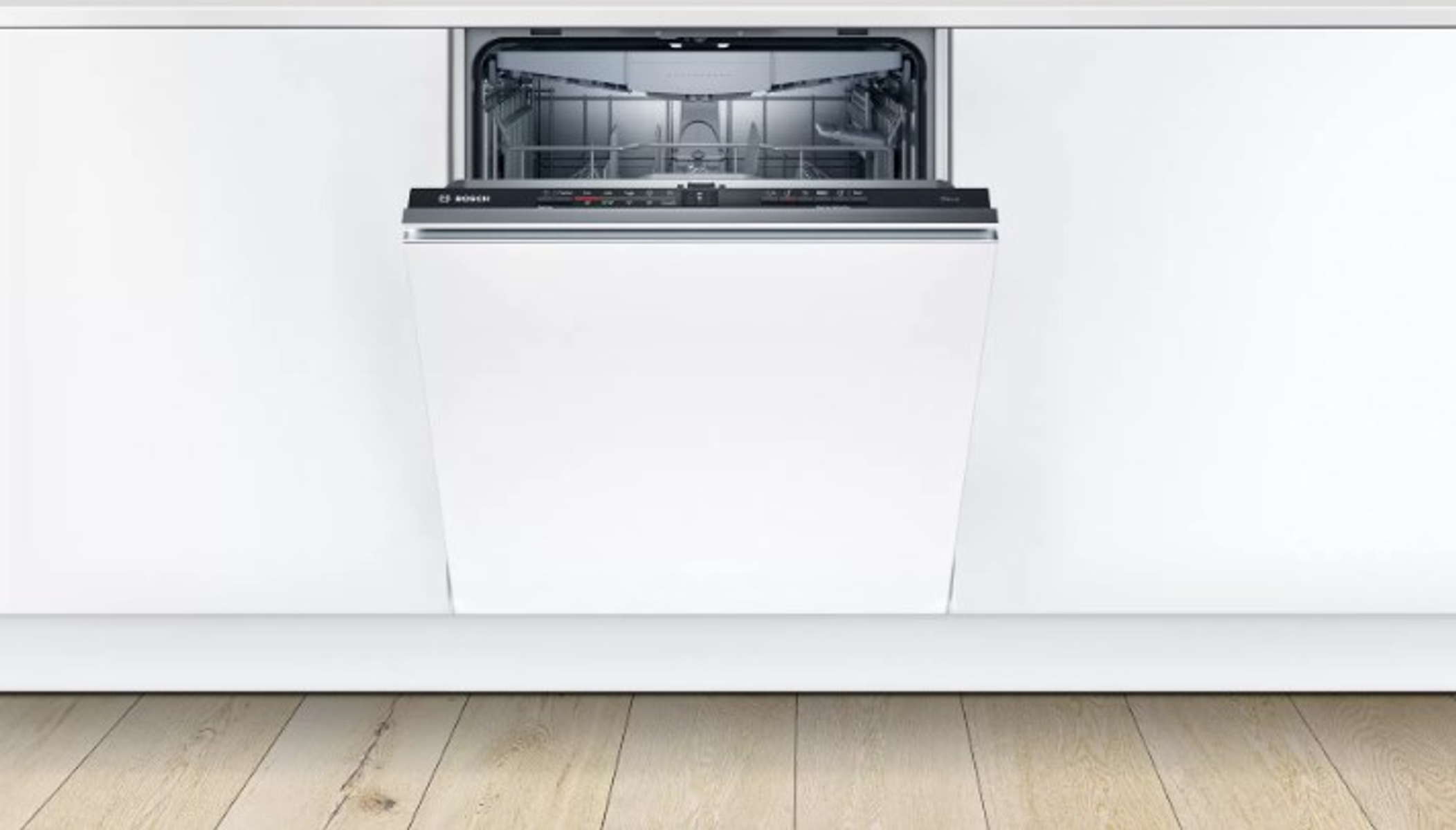 Lavastoviglie bianca aperta in una cucina bianca. Pavimento in legno in primo piano.