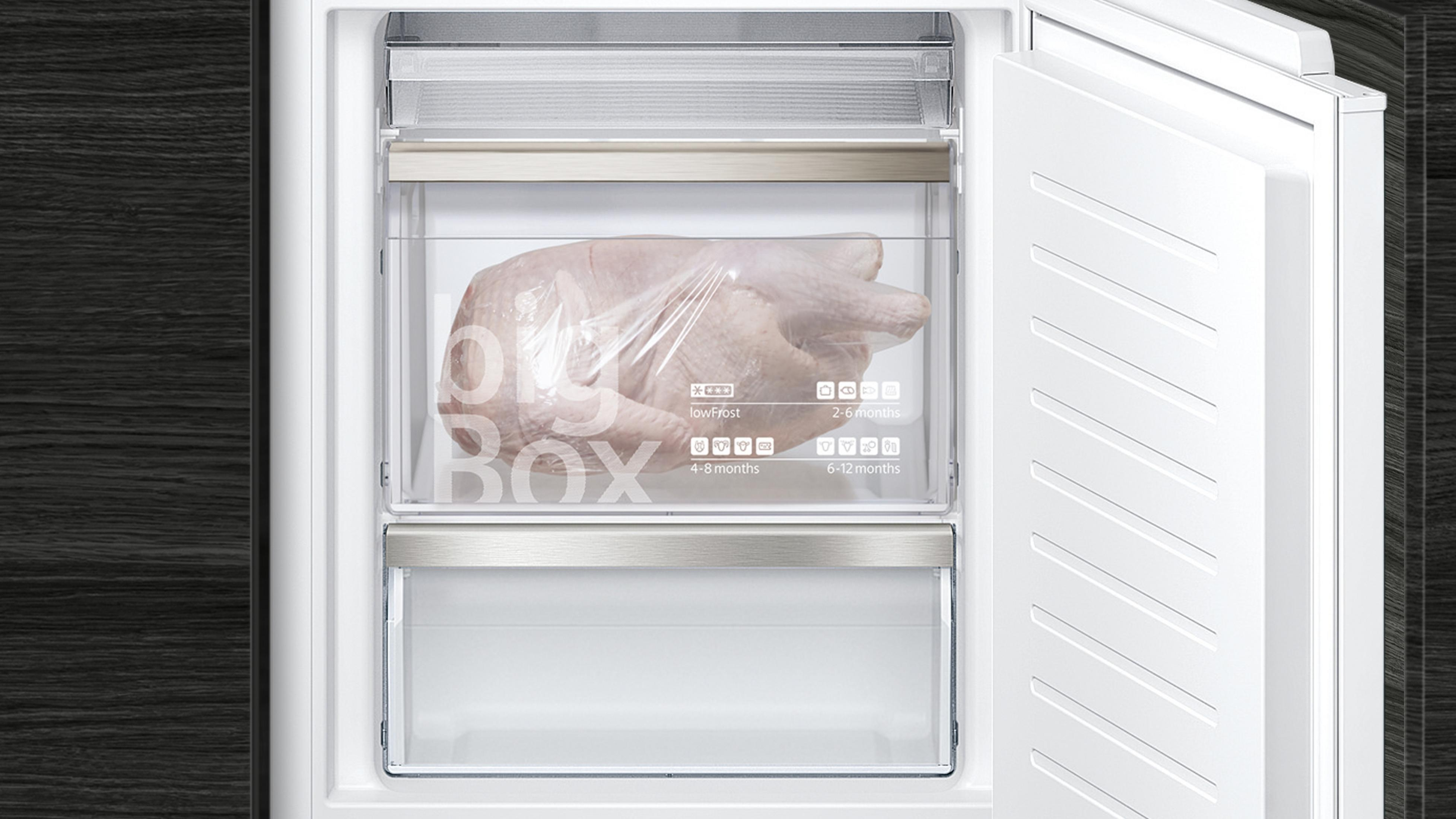 Un refrigerador abierto muestra un pollo envuelto dentro.
