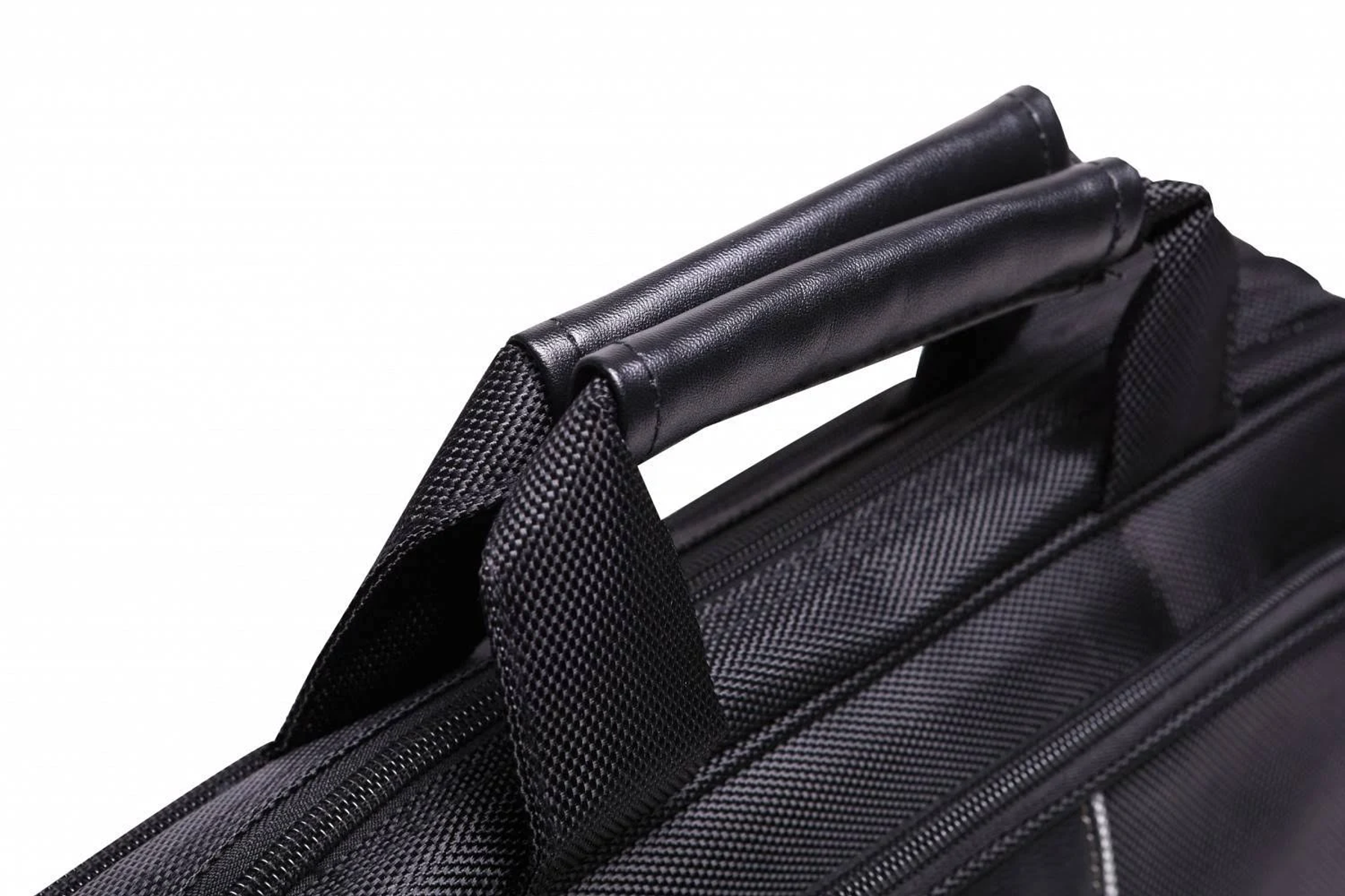 Primo piano di manici di borsa neri attaccati a una borsa nera con cuciture visibili.