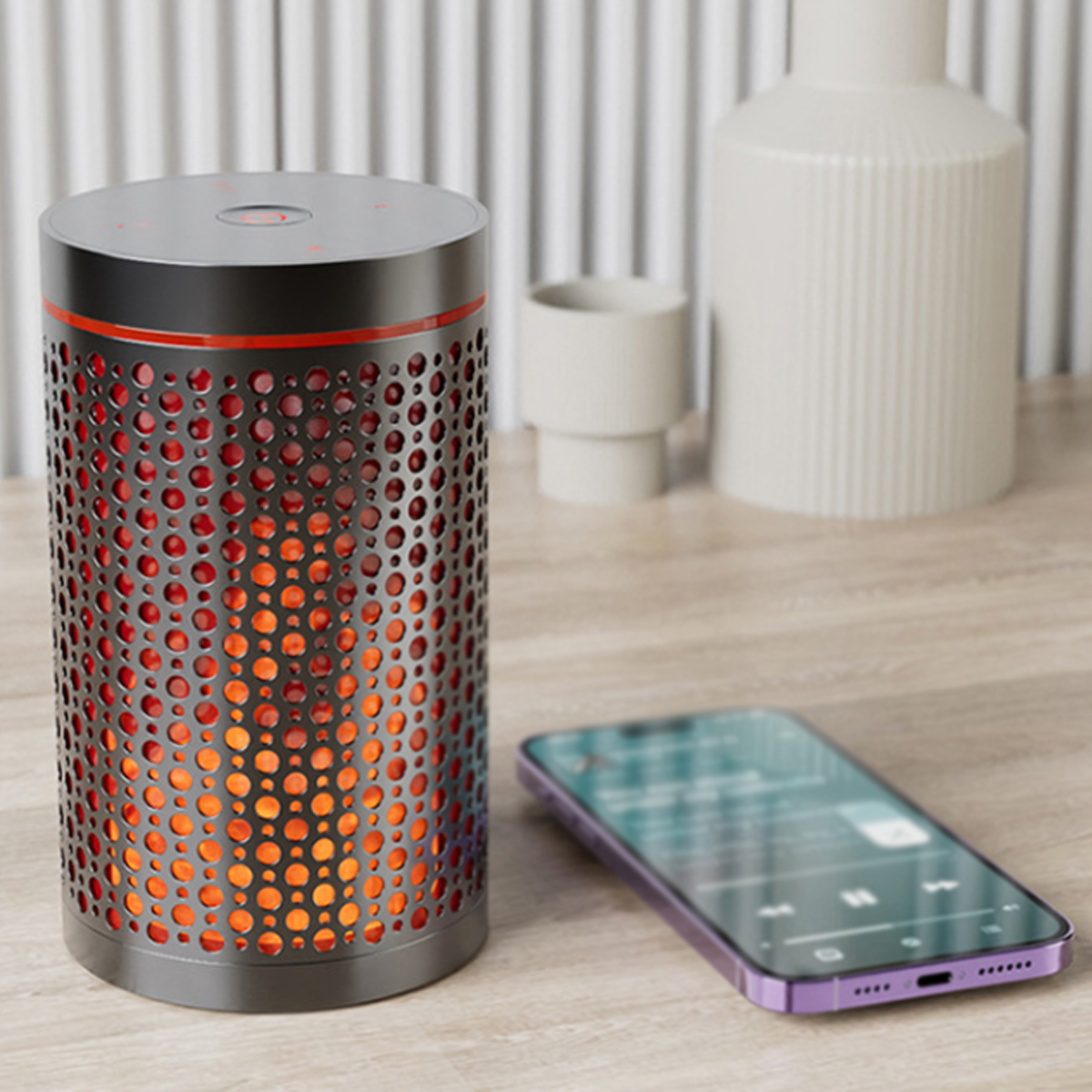 Ein schwarzer und orangefarbener Lautsprecher mit Flammeneffekt und ein lila Telefon auf dem Tisch.