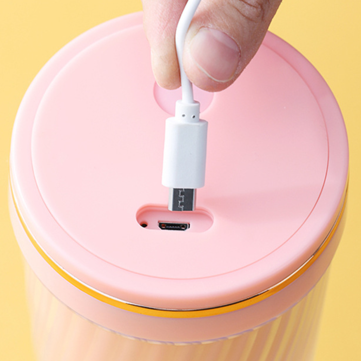 Nahaufnahme eines rosa-goldenen Zylinder-Ladeanschlusses, ein weißes USB-C-Kabel wird eingesetzt.