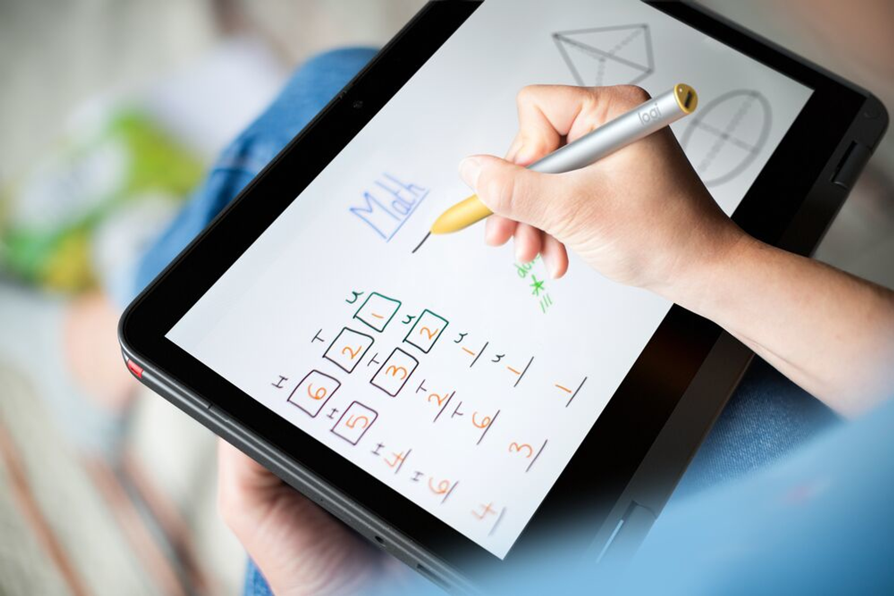 Osoba używa rysika do pisania na ekranie tabletu, wykonując obliczenia matematyczne. Tablet leży na kolanach.