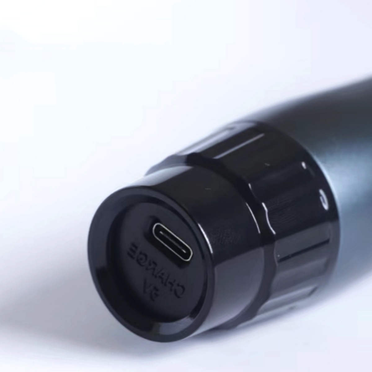 Ein schwarzer USB-C-Anschluss an einem schwarzen Zylinder, möglicherweise Teil eines Geräts, vor weißem Hintergrund.