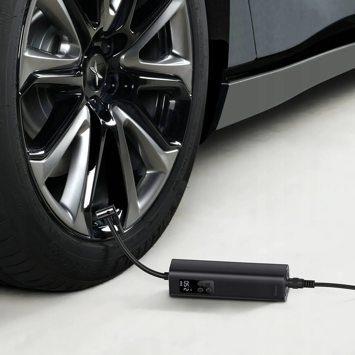 Czarna opona z podłączoną pompką powietrza, pokazująca manometr.