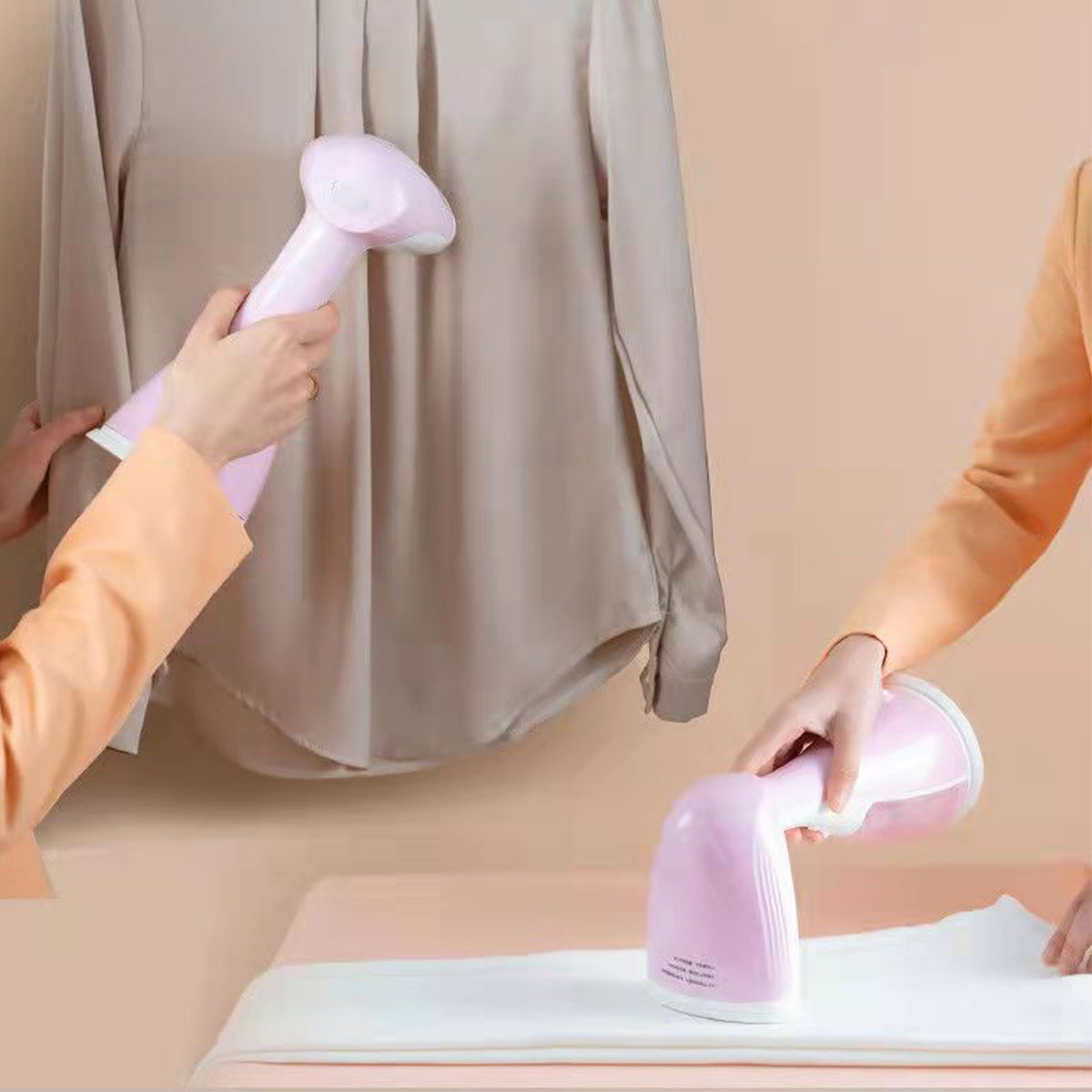 Zwei Personen verwenden rosa Handdampfgeräte für Kleidung an einem Hemd, eine dampft und eine hält es.