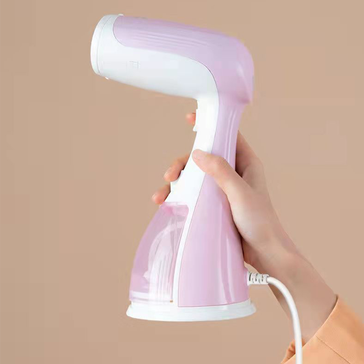 Ein rosa-weißer Kleidungsdämpfer, der von einer Hand gehalten wird, vor beigem Hintergrund.