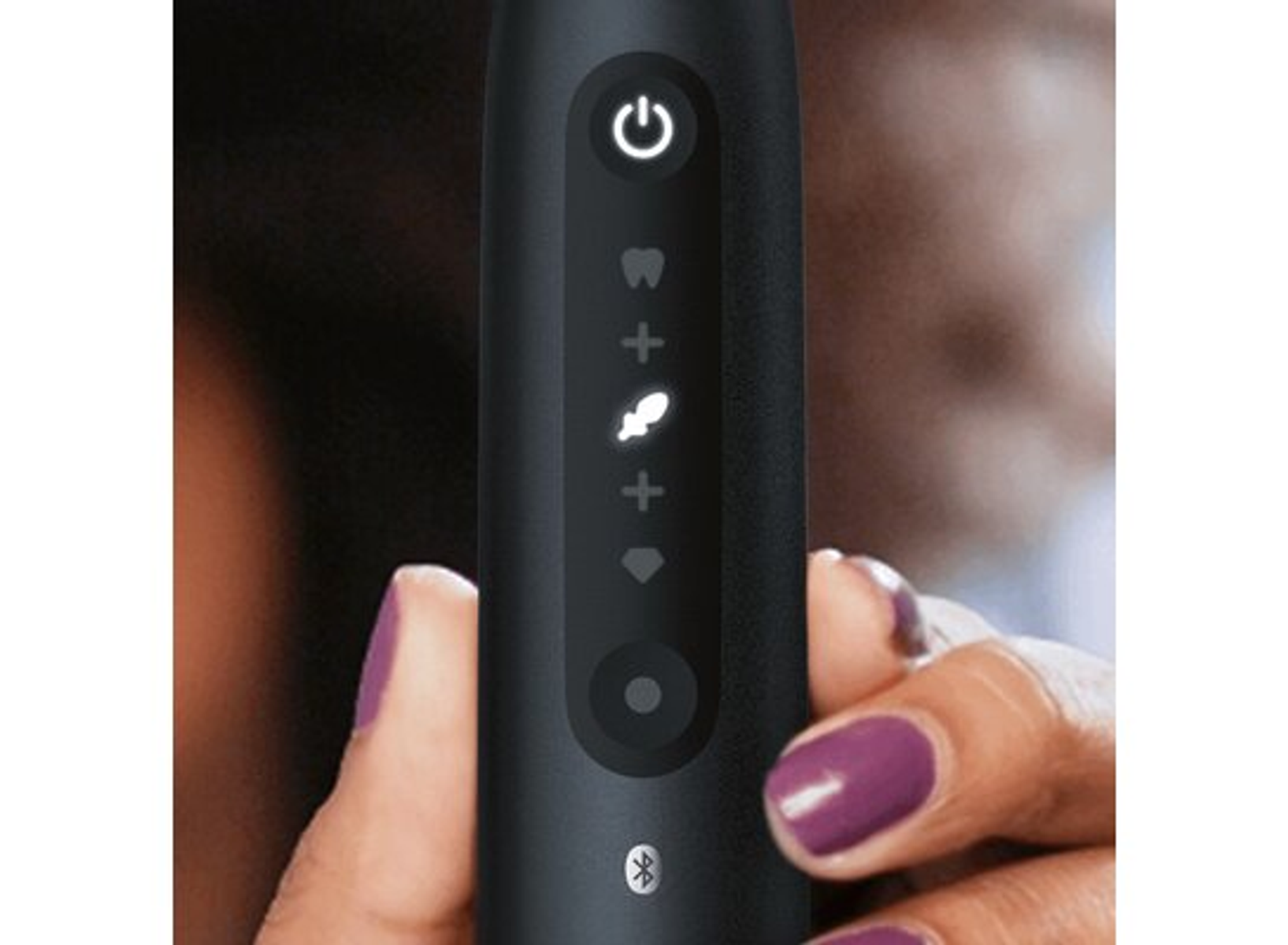 Zbliżenie czarnej elektrycznej szczoteczki do zębów pokazującej ikony i przycisk zasilania.