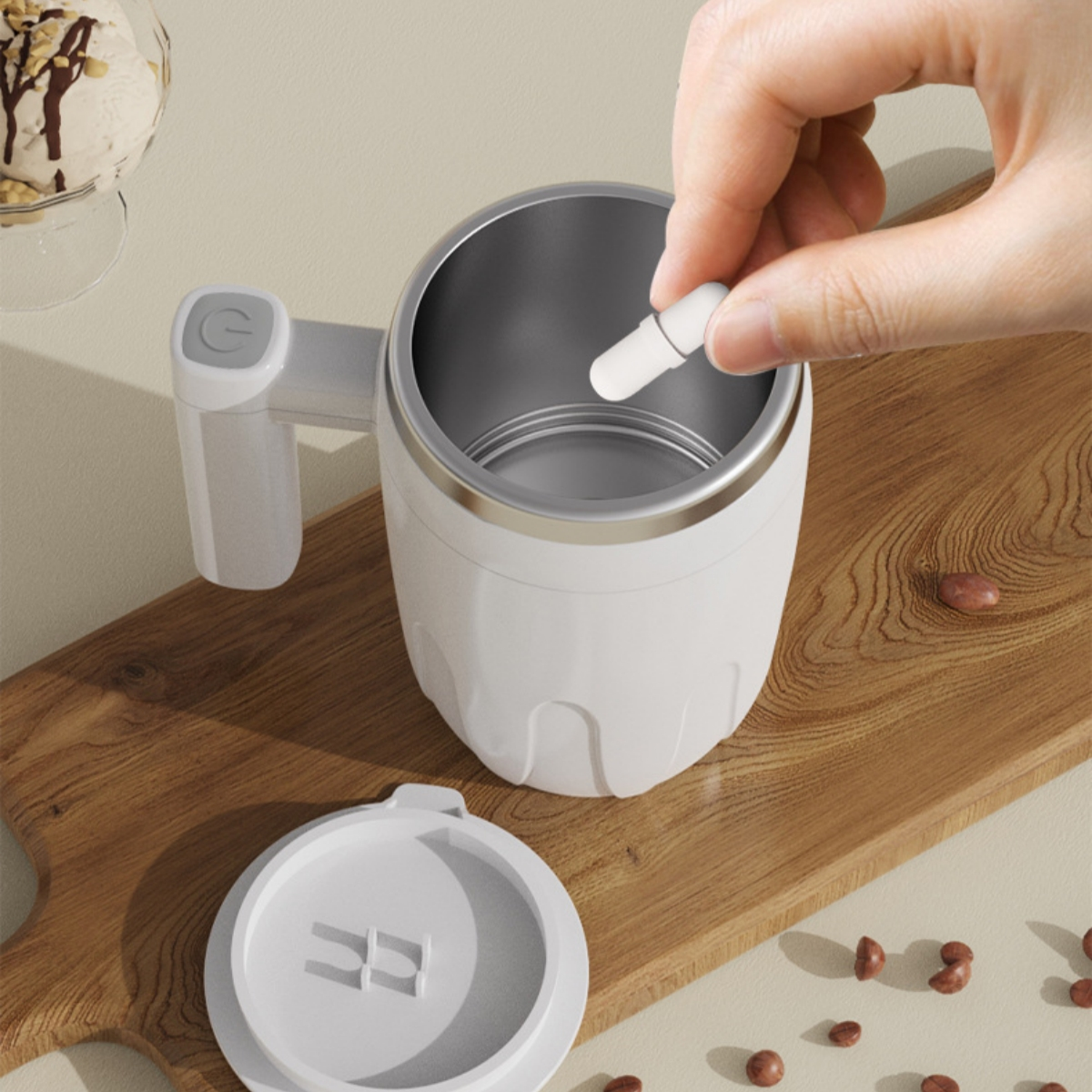 Weißer Becher mit Henkel und Deckel, eine Person gibt etwas in den Inhalt. Holzoberfläche.