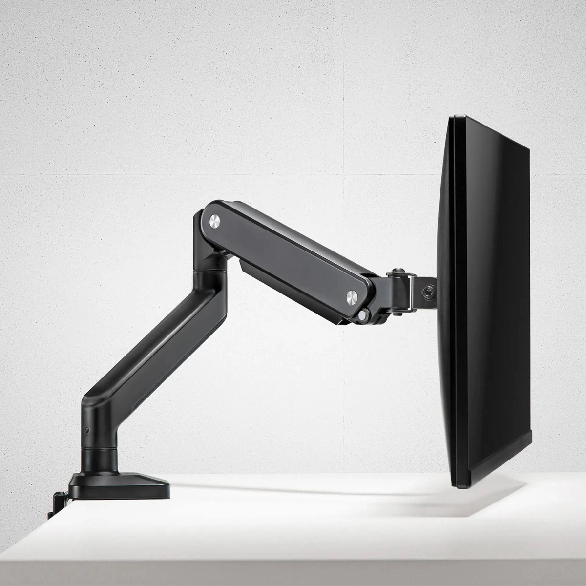 Schwarzer Monitor an einem schwarzen, verstellbaren Arm auf weißer Fläche.