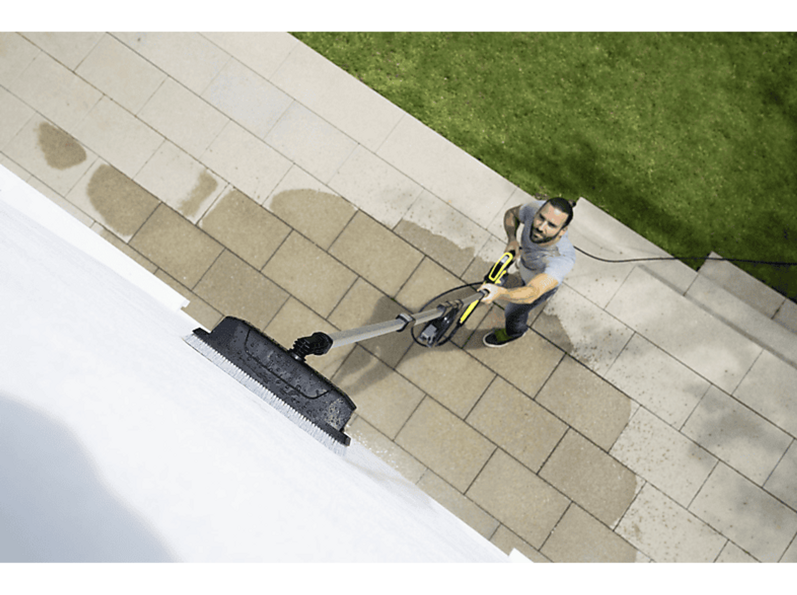 Un hombre limpiando una pared blanca con una hidrolavadora.