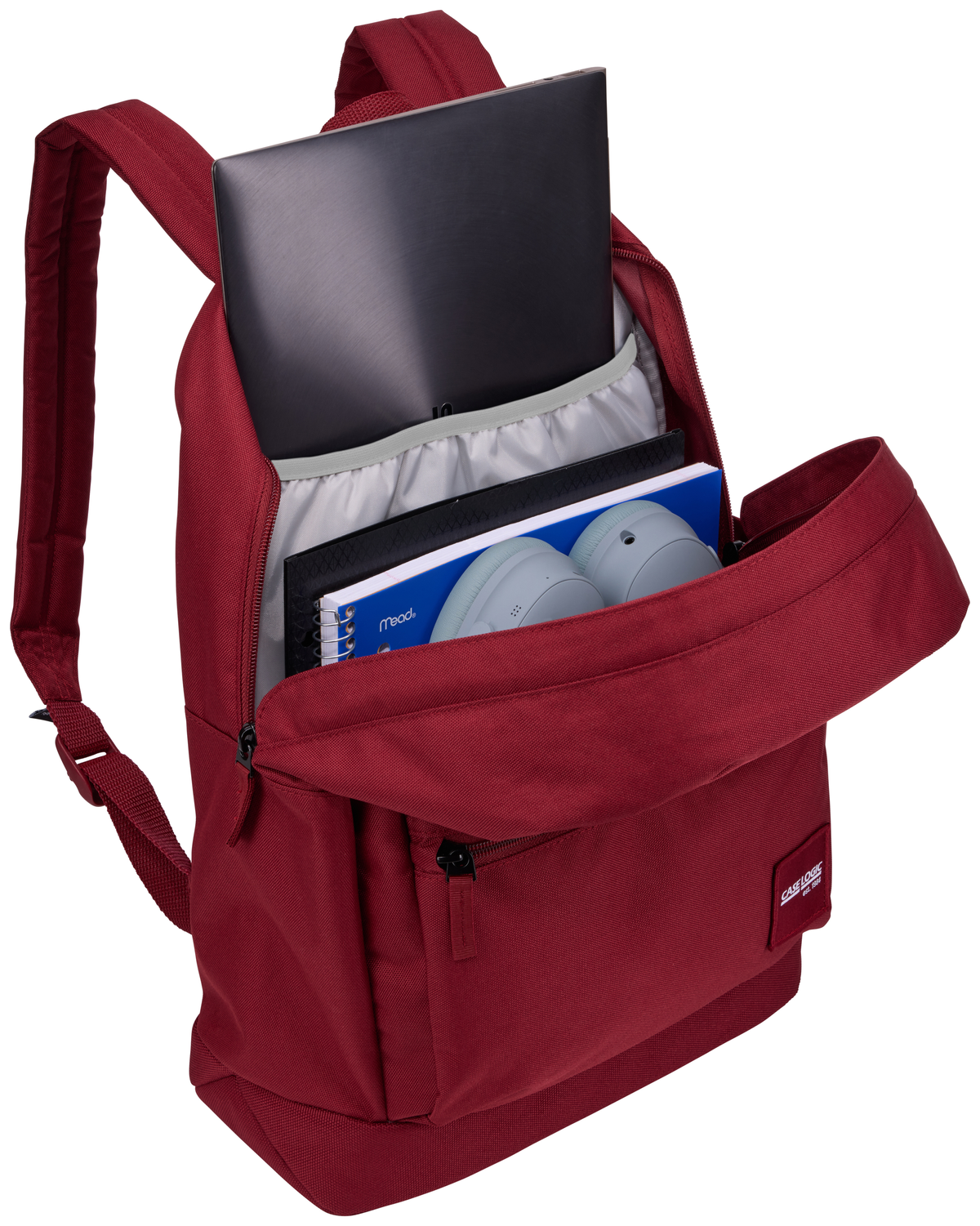 Zaino rosso aperto con laptop, quaderni e cuffie all'interno. Cerniera nera visibile.