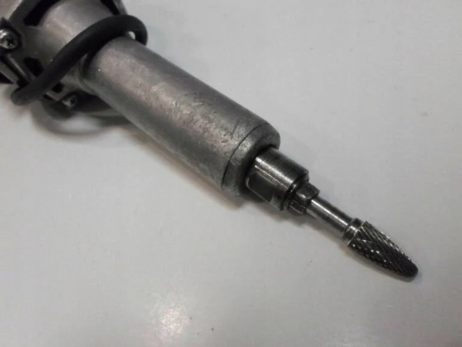 Un utensile rotante in metallo con una punta da trapano. L'utensile è argentato con una fascia nera.