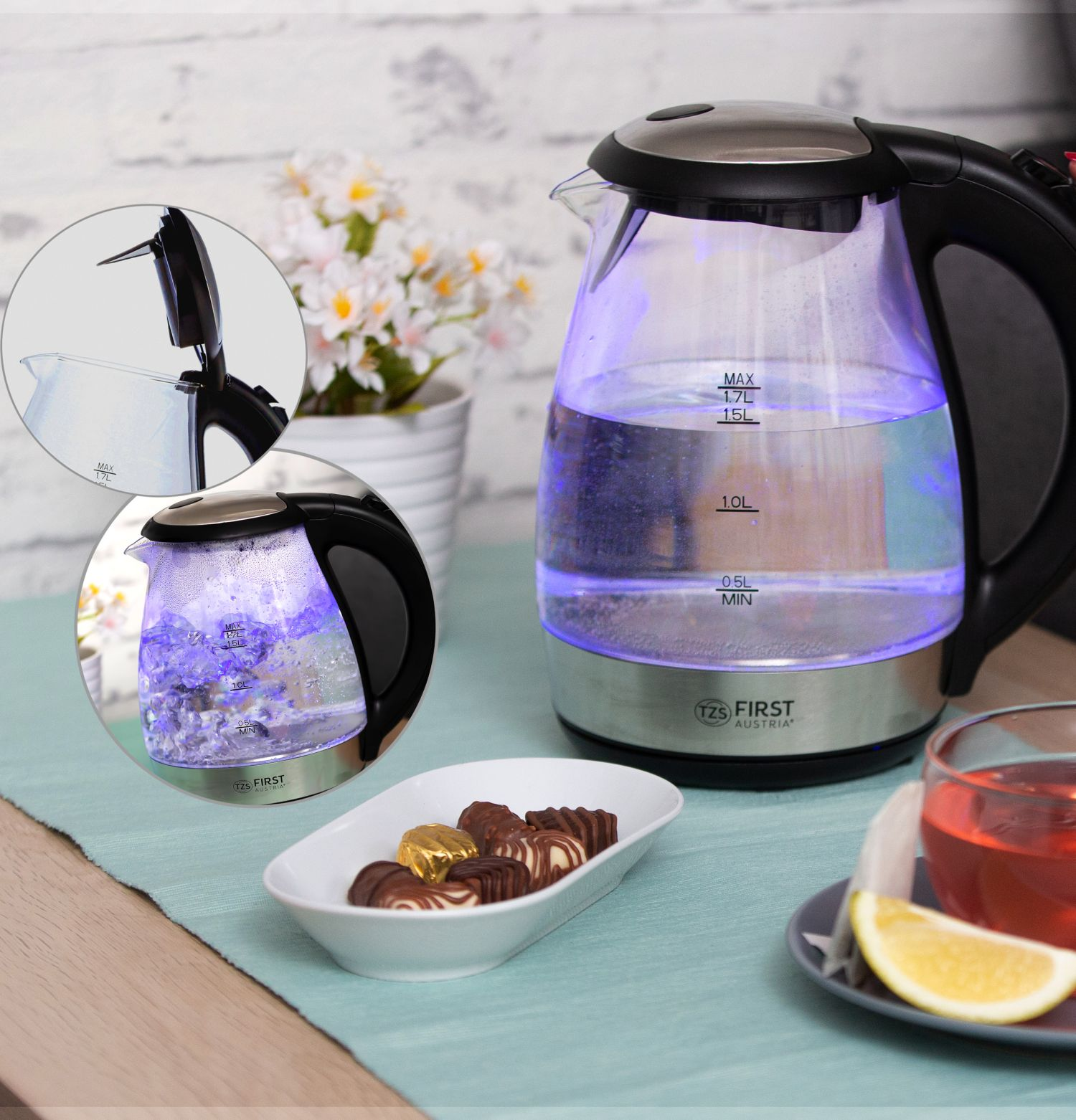 Ein elektrischer Wasserkocher mit blauen Innenlichtern, Pralinen und einer Teetasse.