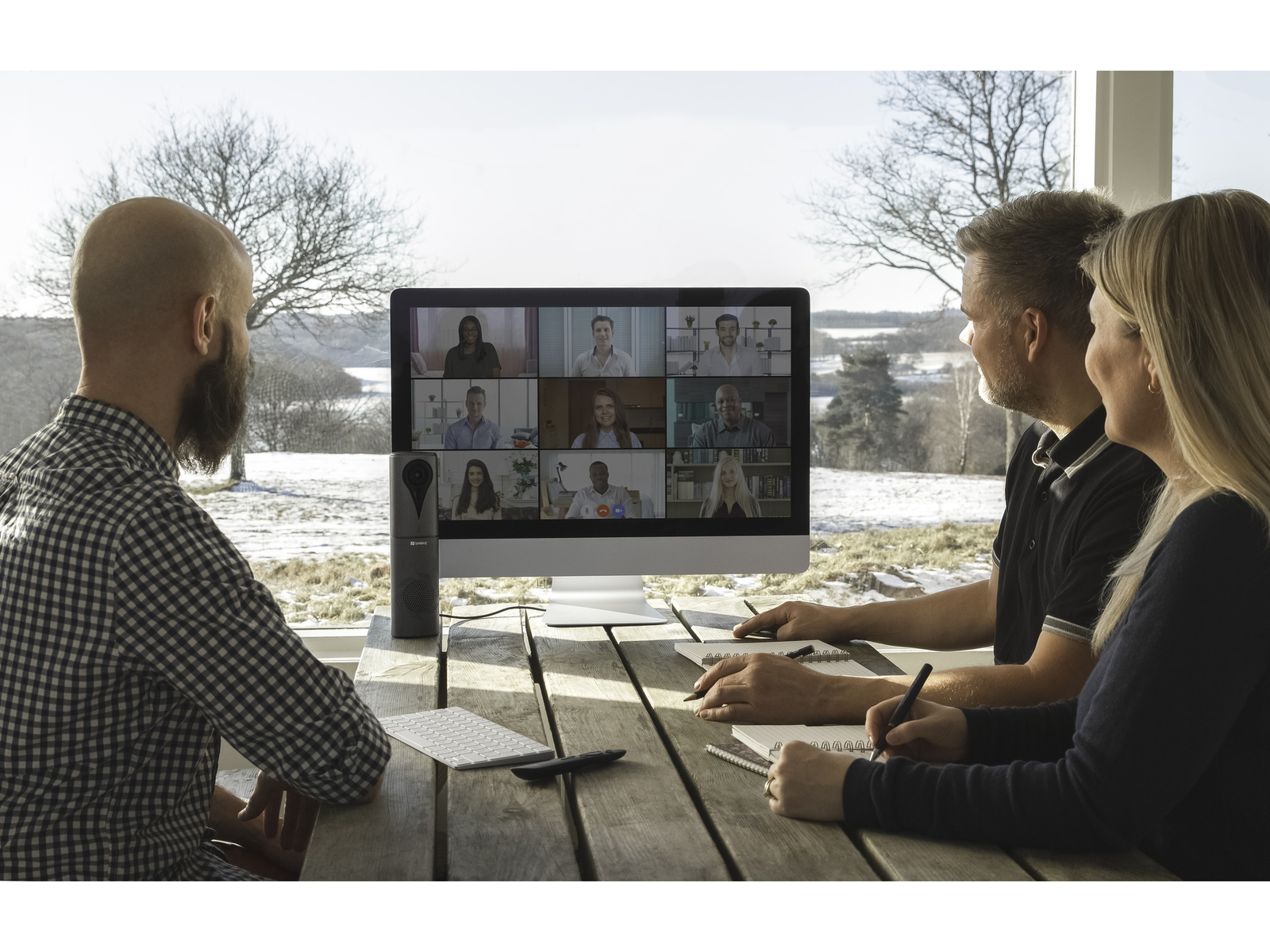 Wideorozmowa grupowa na ekranie, ludzie przy stole.