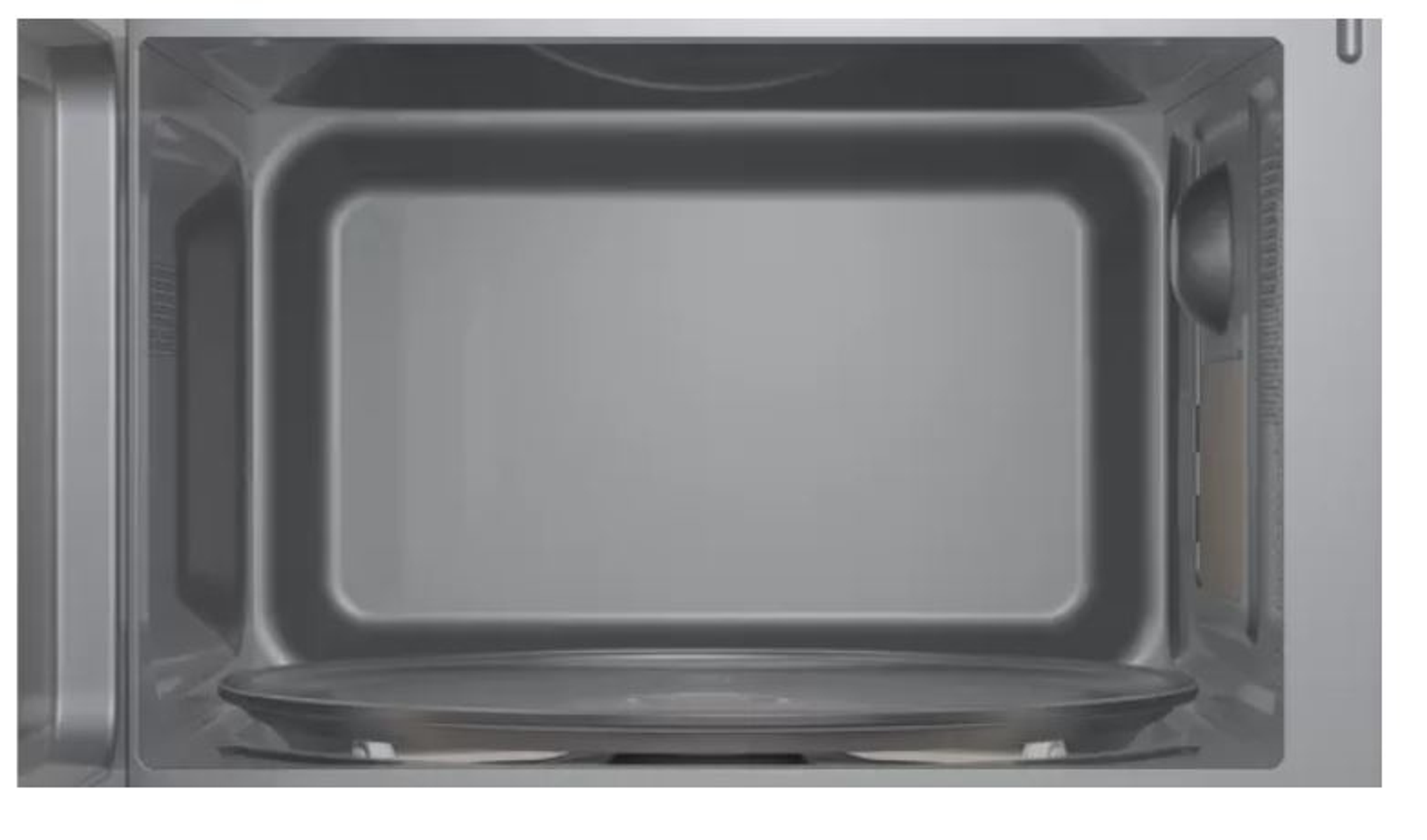 Wnętrze kuchenki mikrofalowej, ze szklanym talerzem i łyżką.