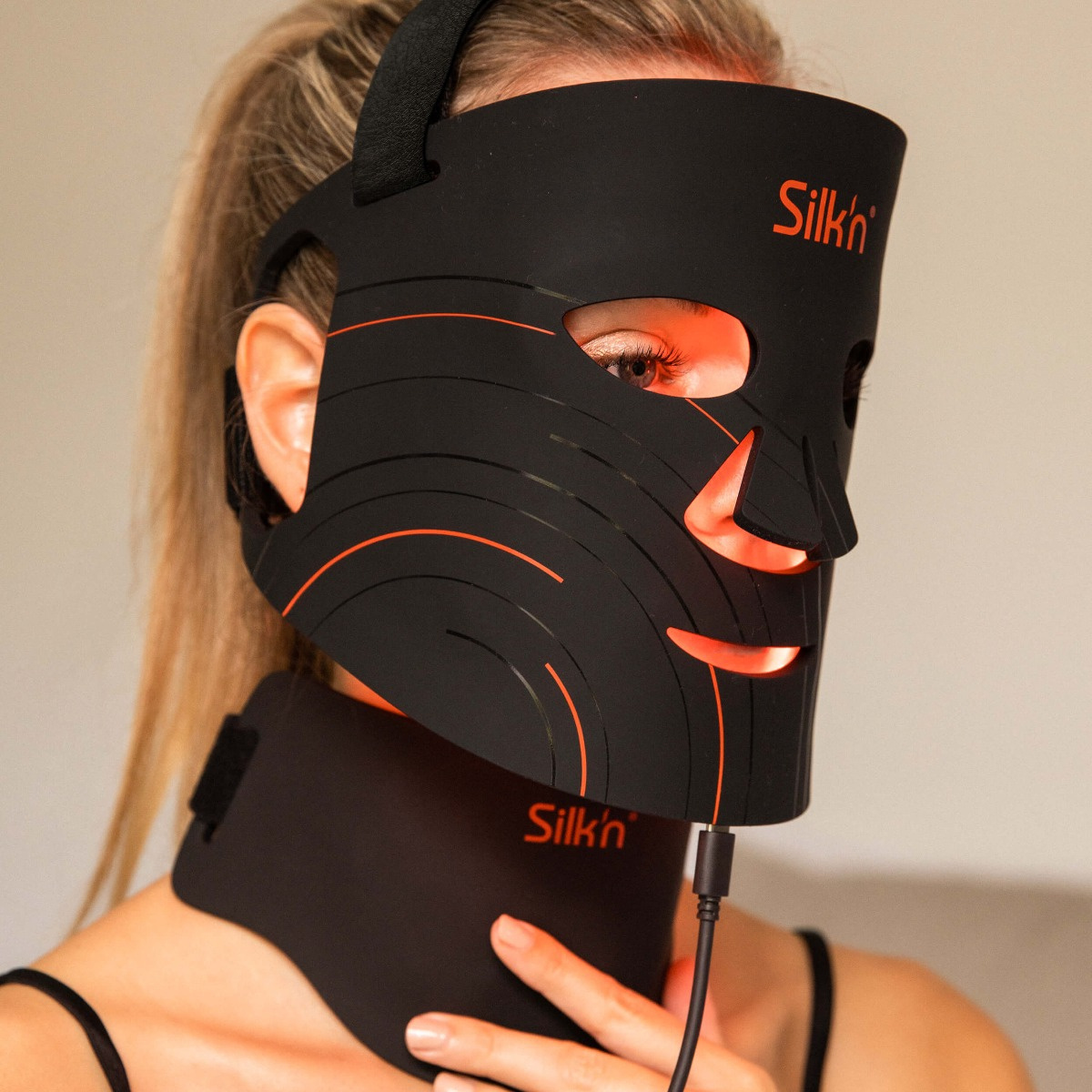 Eine Frau trägt eine schwarze LED-Gesichtsmaske. Sie hat rote Lichter an.