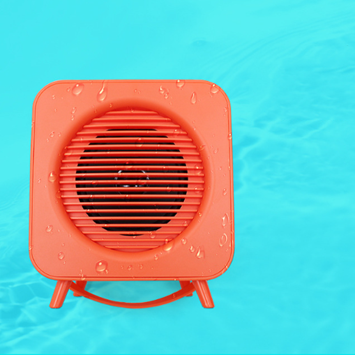 Ein orangefarbener, quadratischer Lautsprecher mit kreisförmigem Lautsprechergitter im Zentrum liegt im Wasser.