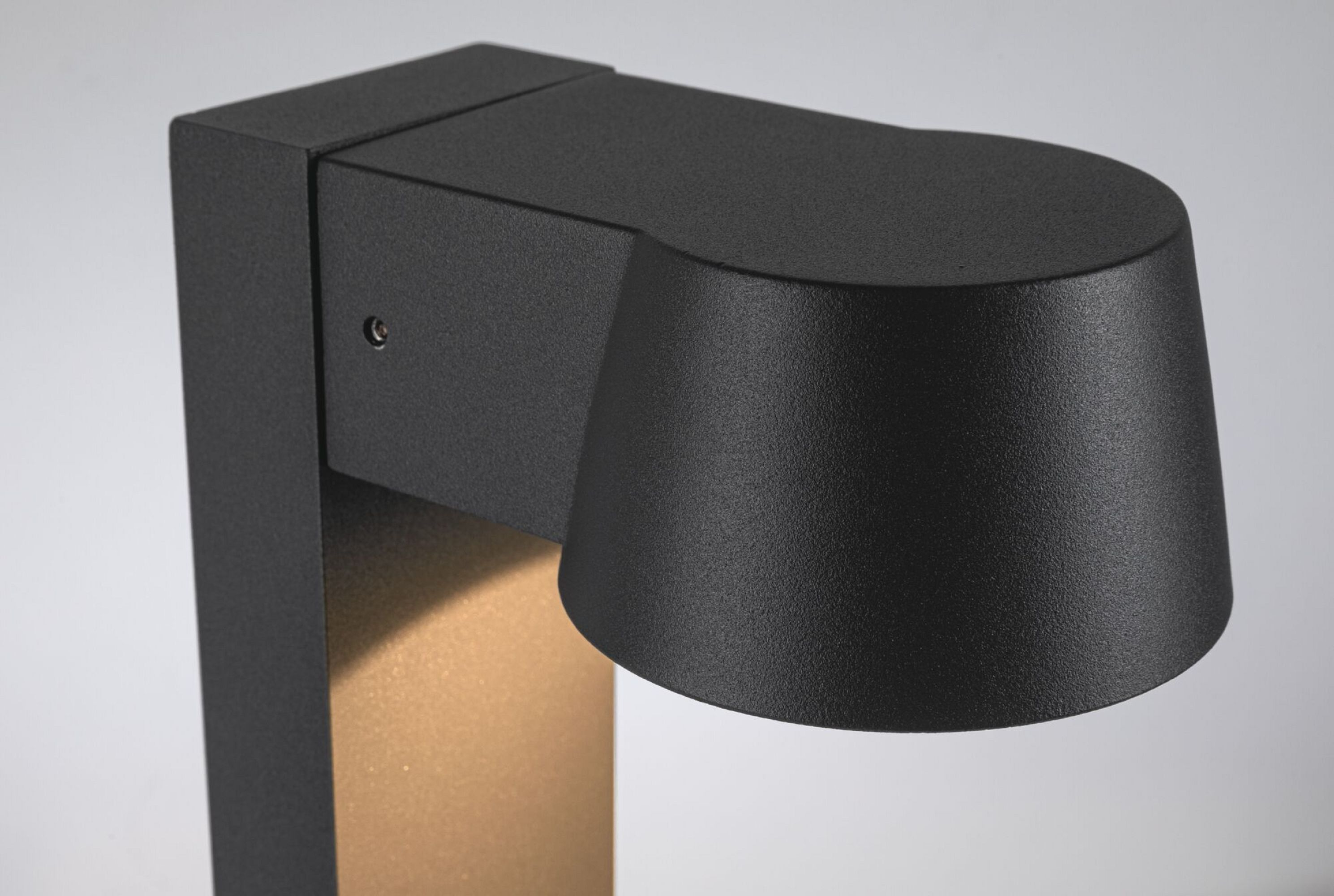 Czarna oprawa oświetleniowa zewnętrzna ze złotym akcentem na białym tle.